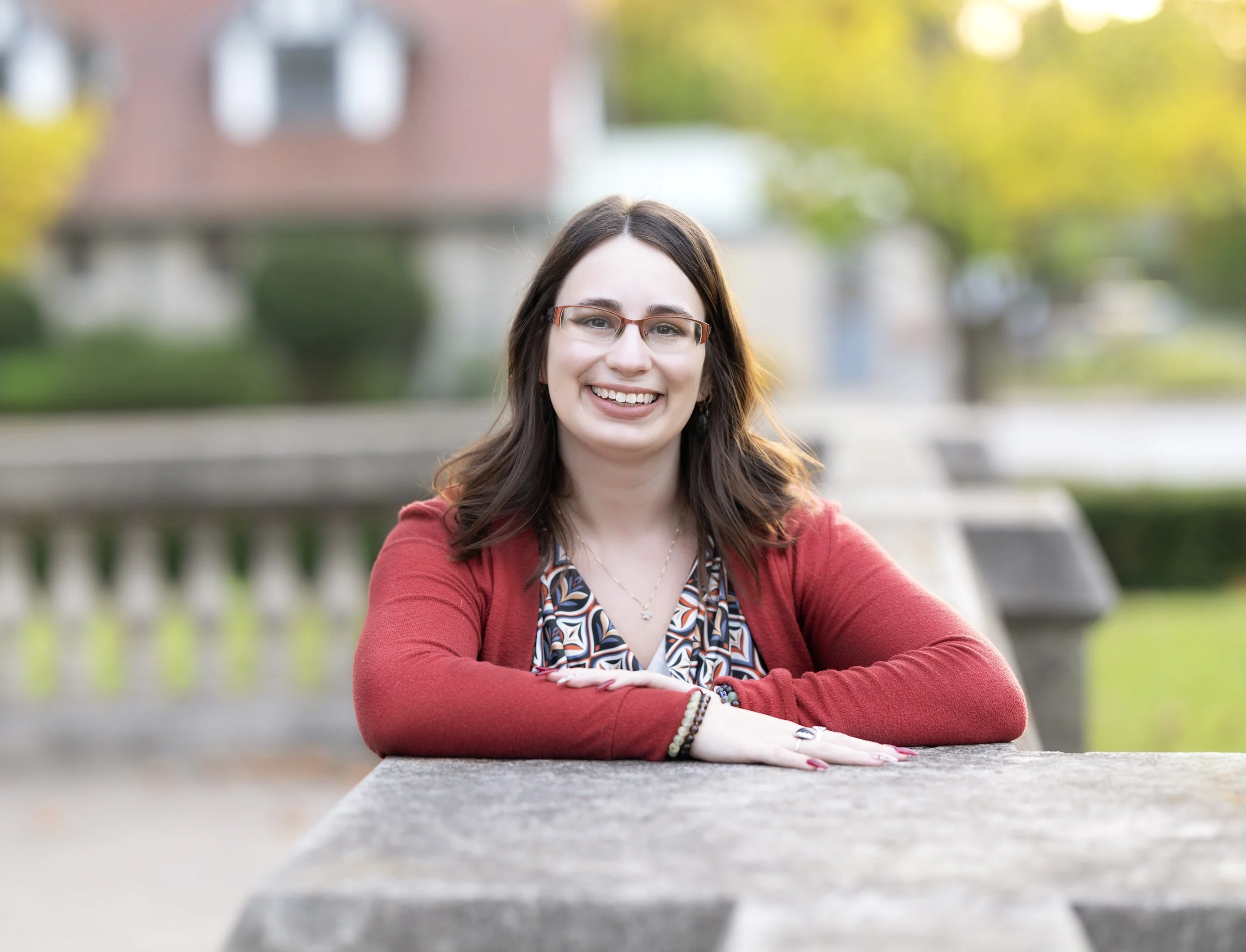 A female substance use therapist in Nova Scotia at a table outside wearing a red cardigan