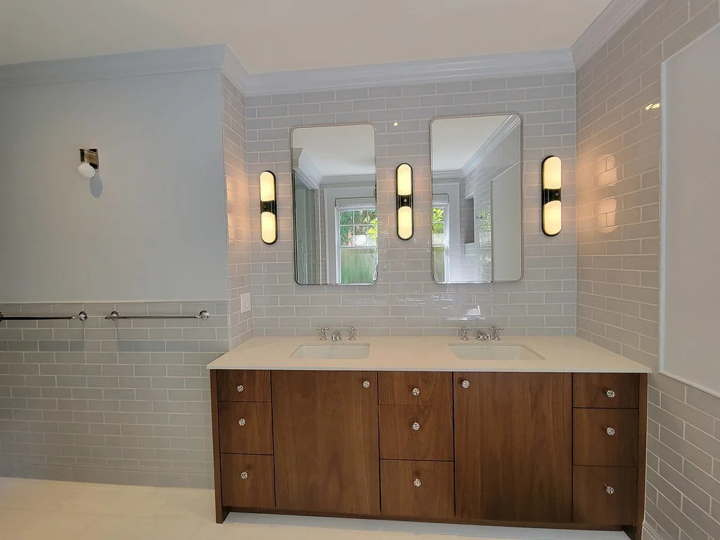 Modern bathroom vanity with double sinks, wooden cabinets, two mirrors, and vertical wall sconces.