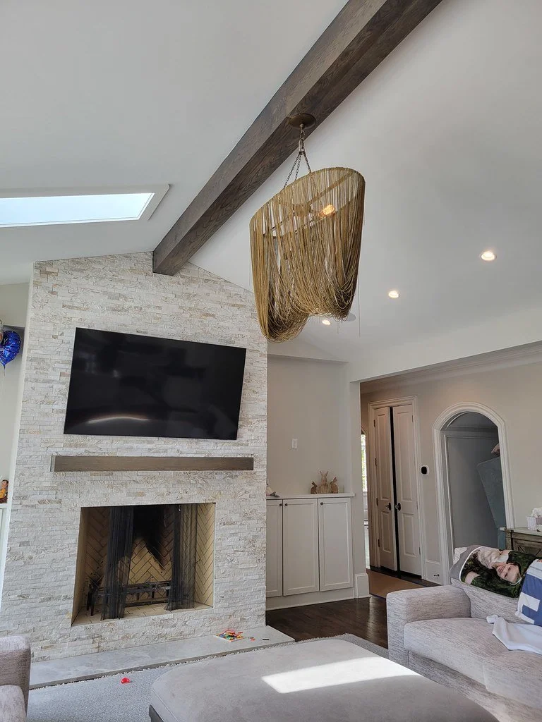 Living room with a fireplace, flat-screen TV, and a hanging light fixture made of cascading strings or beads.