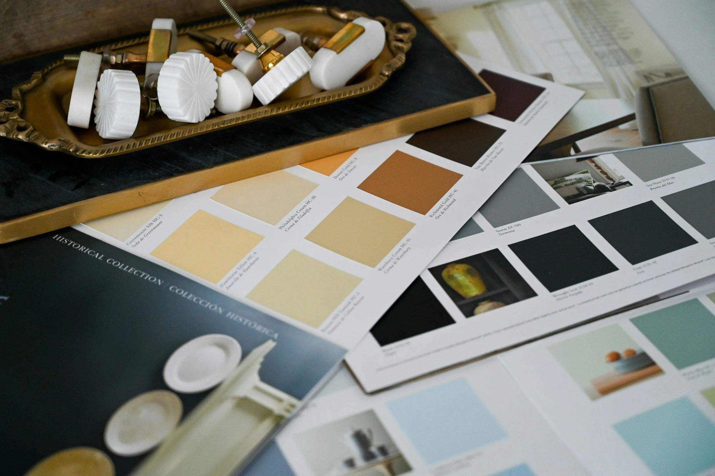 Color sample and paint swatch cards on a table with a decorative tray containing molding samples.