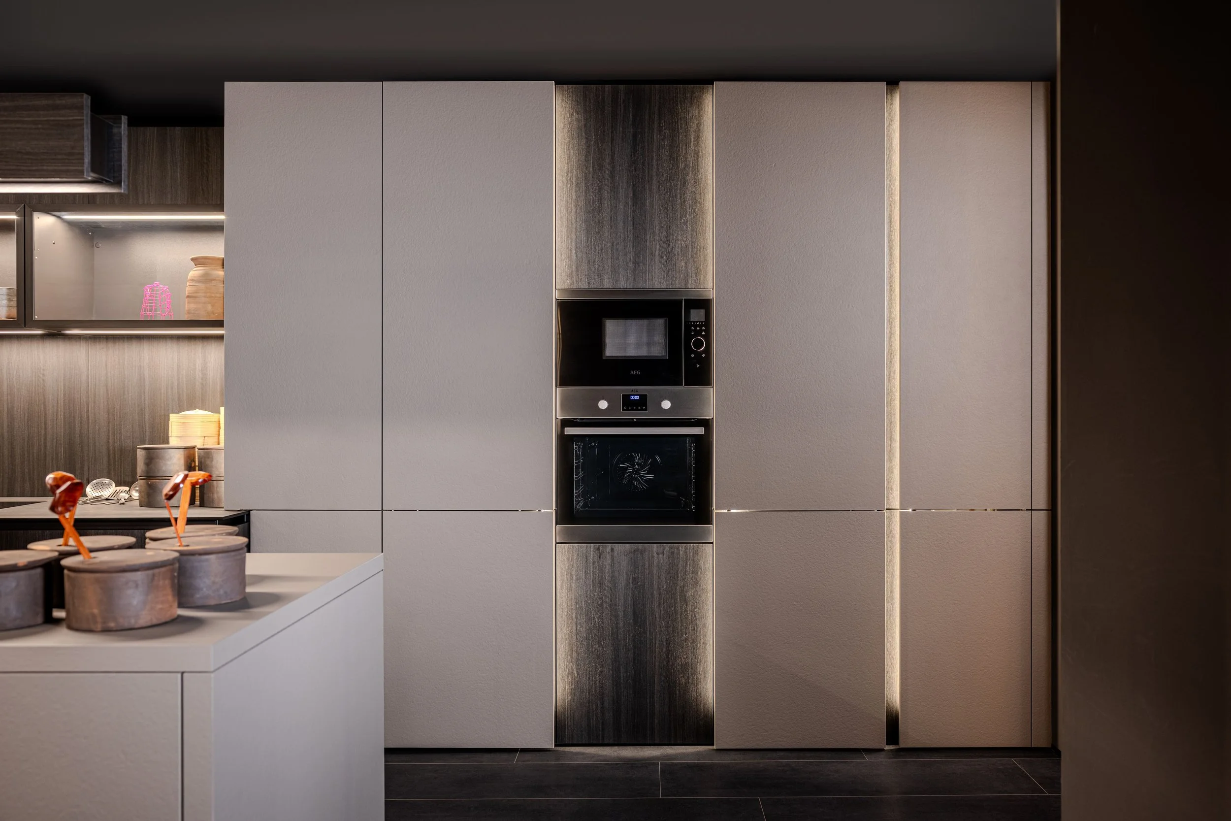 Modern kitchen with built-in oven and microwave, beige cabinets, and dark wood accents.