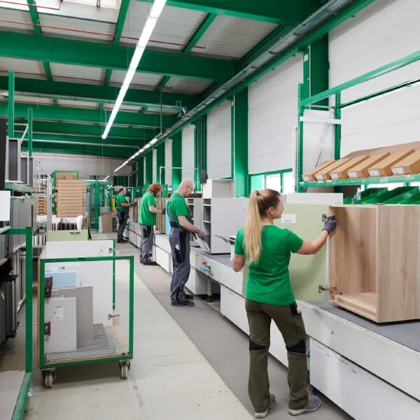 Workers assembly line manufacturing furniture in a factory with metal and wood components. Sachsenküchen factory facility based in Dresden. German Engineering. Luxury kitchens. State-of-the-art engineering technology in German kitchen manufacturing.