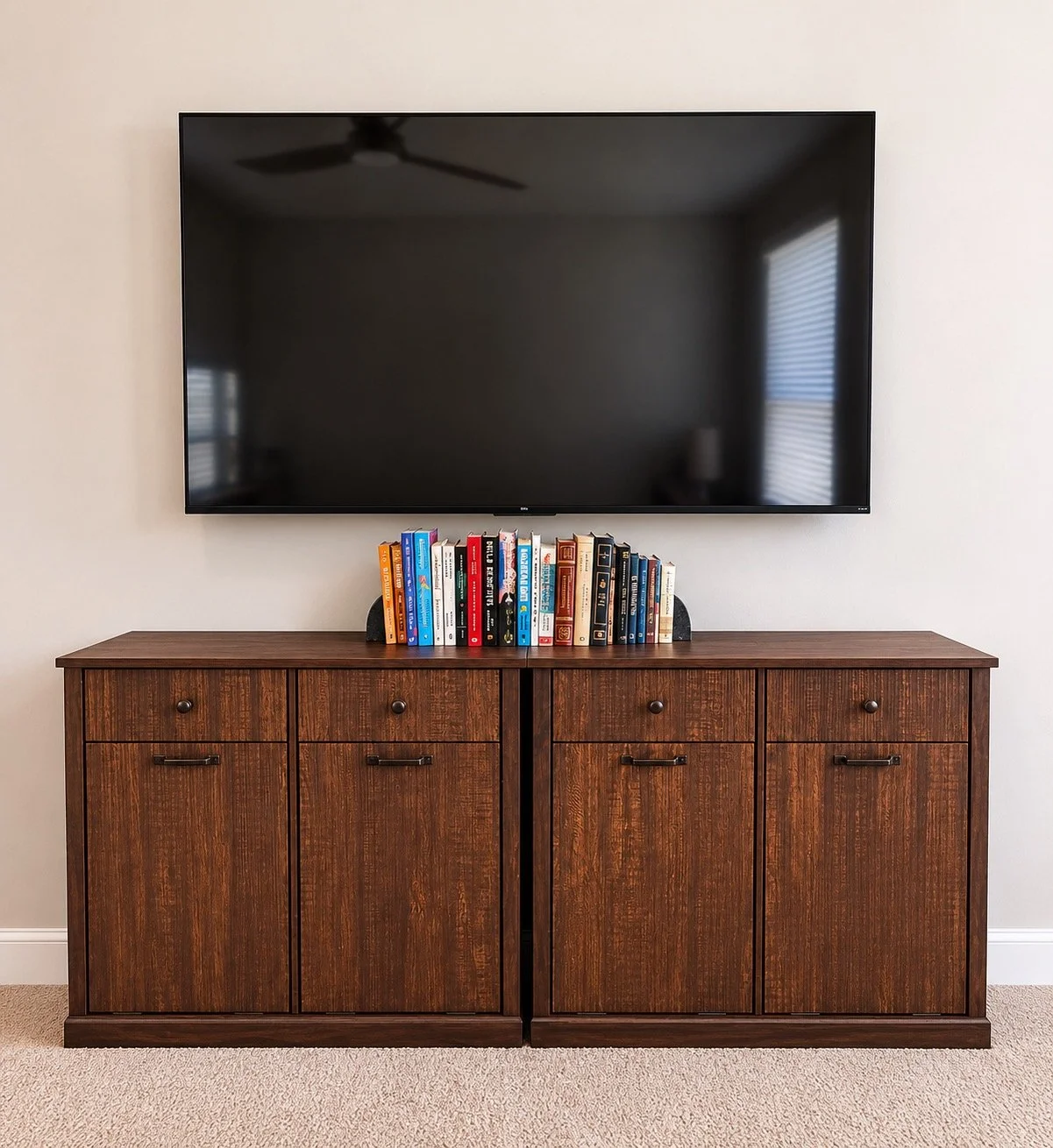 Wooden cabinet with books on top and a large flat-screen TV mounted on the wall above.