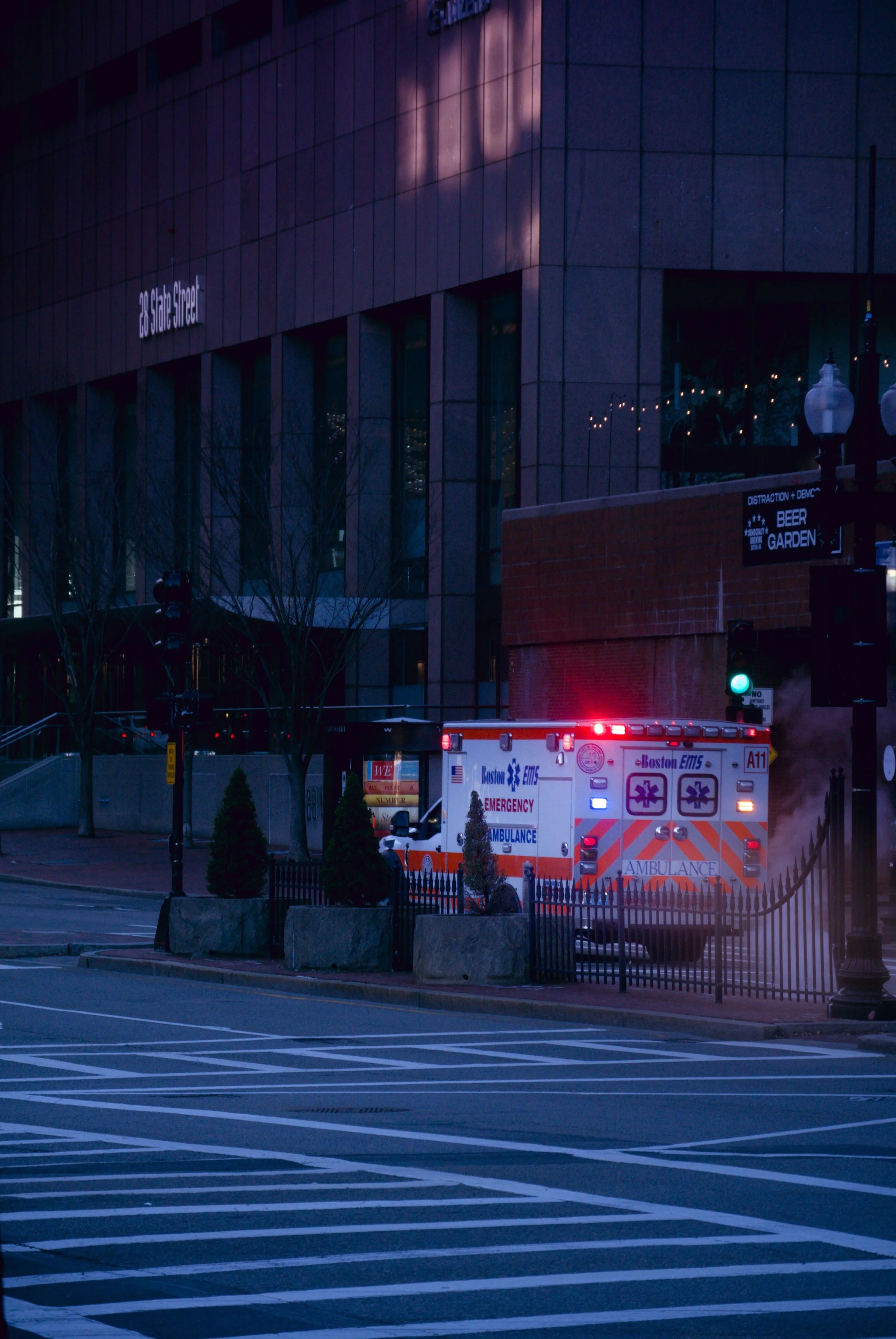 Nighttime urban scene with an ambulance at a crosswalk and a building with illuminated windows
