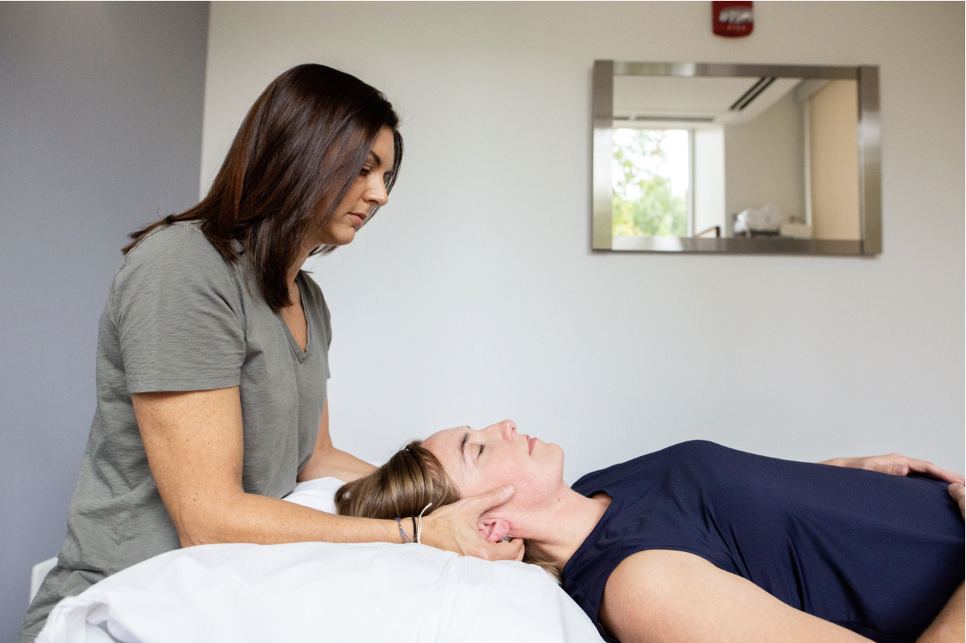 A physical therapist working on a patient's neck with manual therapy inside of a session
