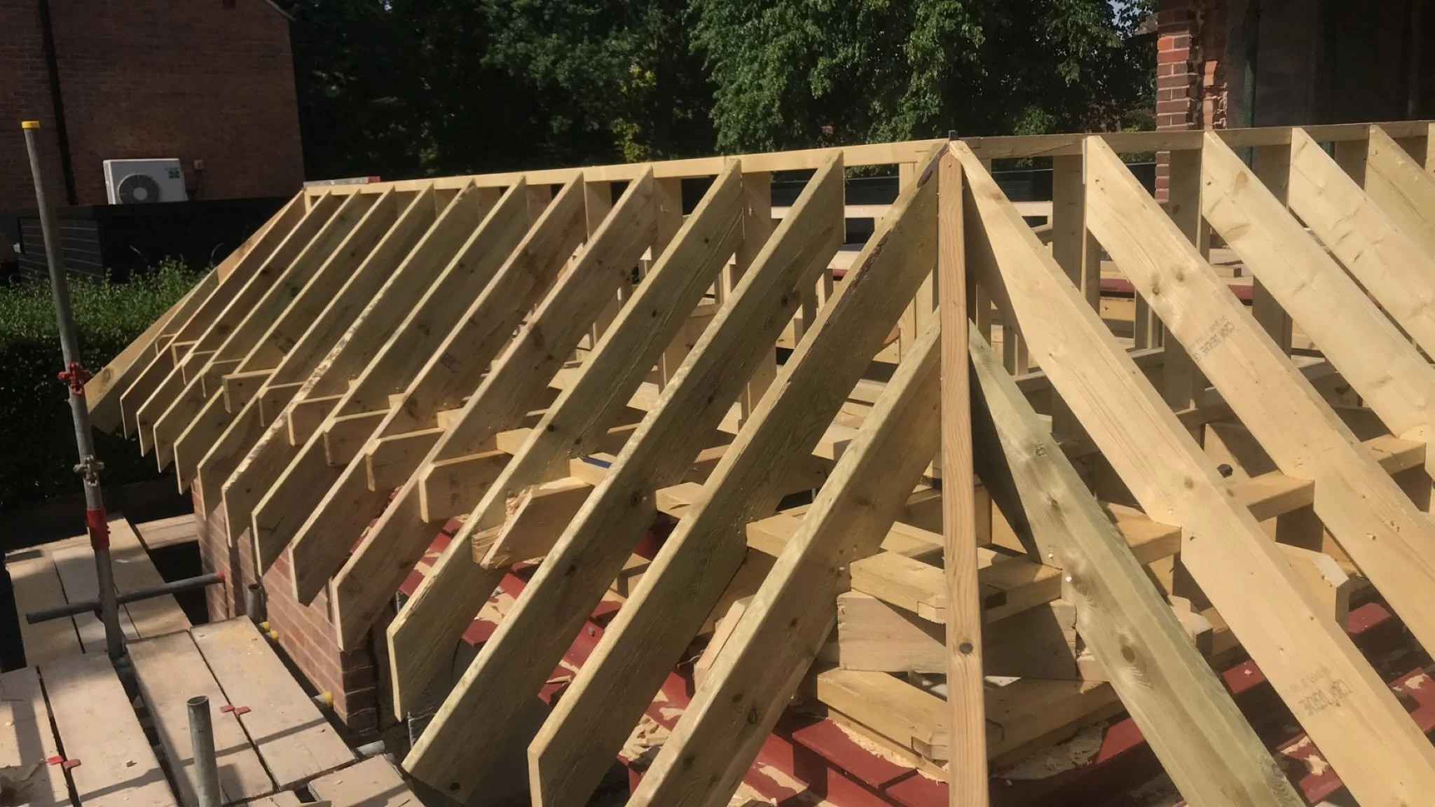 Wooden roof framework in progress, surrounded by scaffolding.
