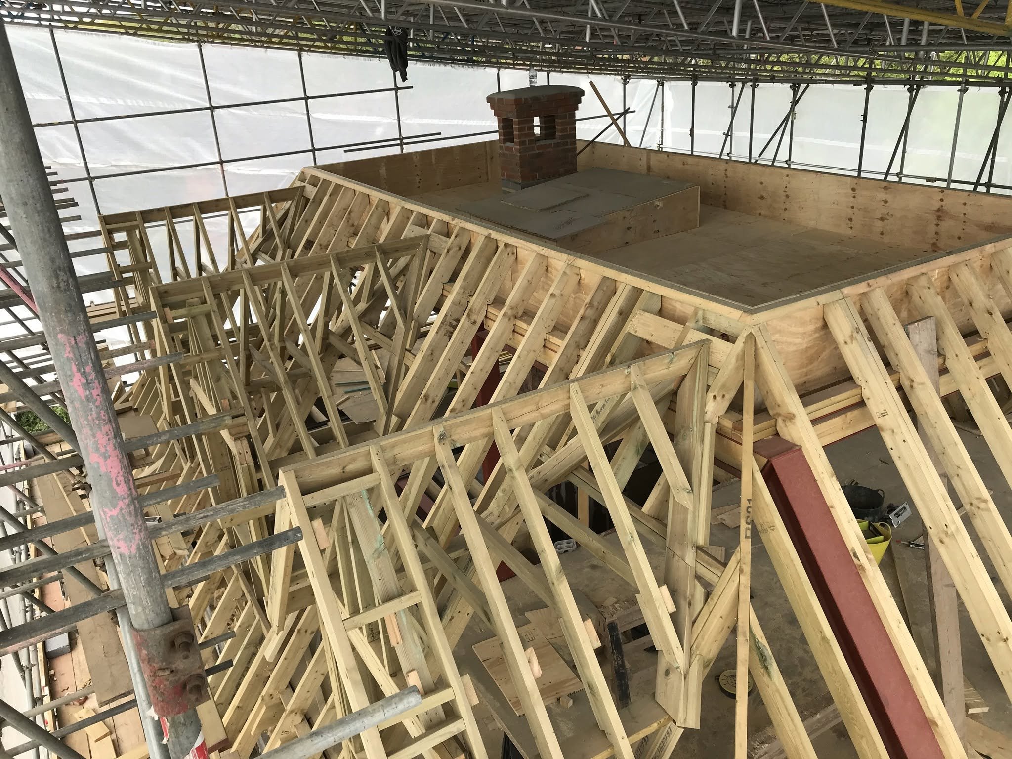 Construction site with wooden framing for a new roof on show under a protected scaffolding roof.