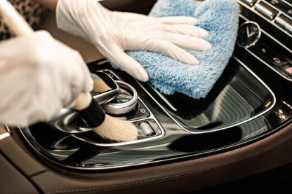 Person cleaning a car's gear shift with a cloth and wearing gloves.