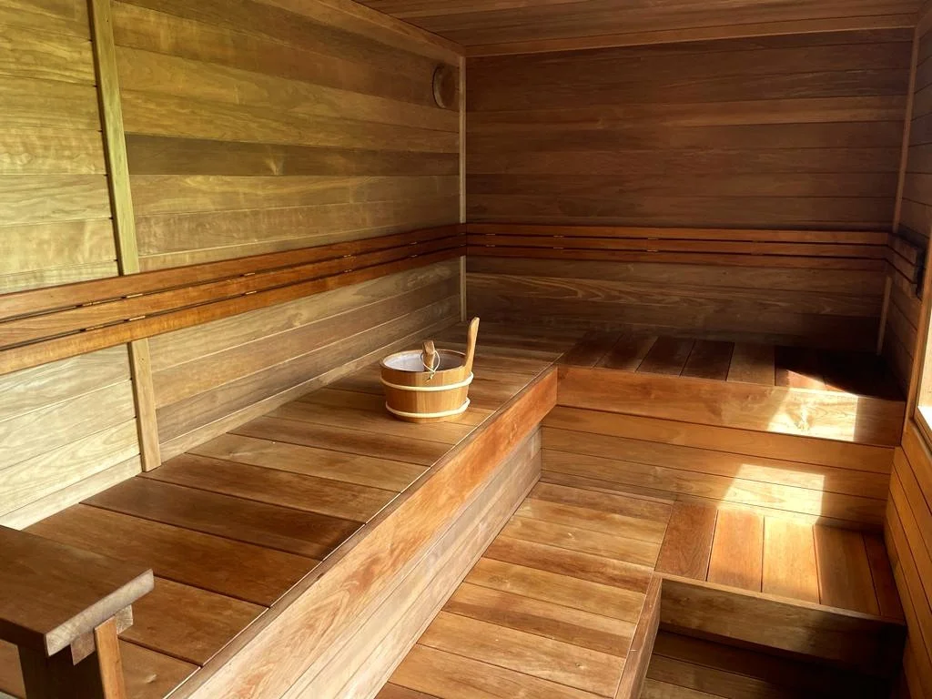 Interior of a wooden sauna with benches and a bucket with a ladle.