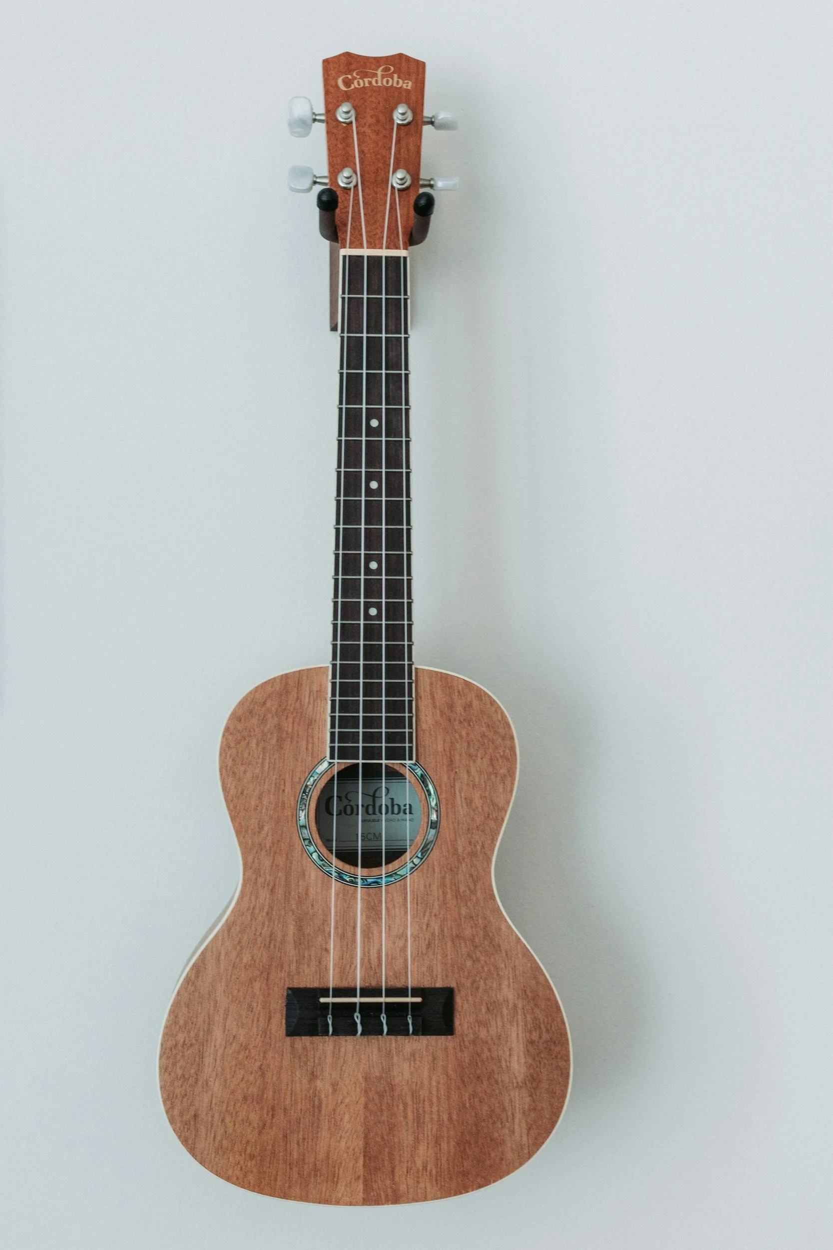 A small wooden ukulele with a Córdoba label on the sound hole, placed against a plain white background.