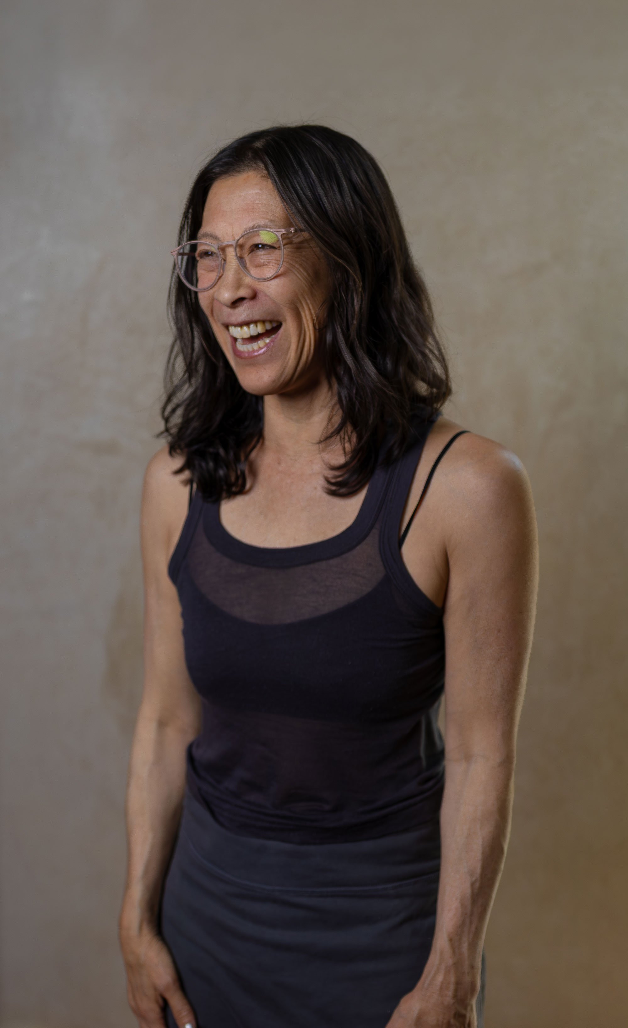 Woman with dark hair laughing in dark top