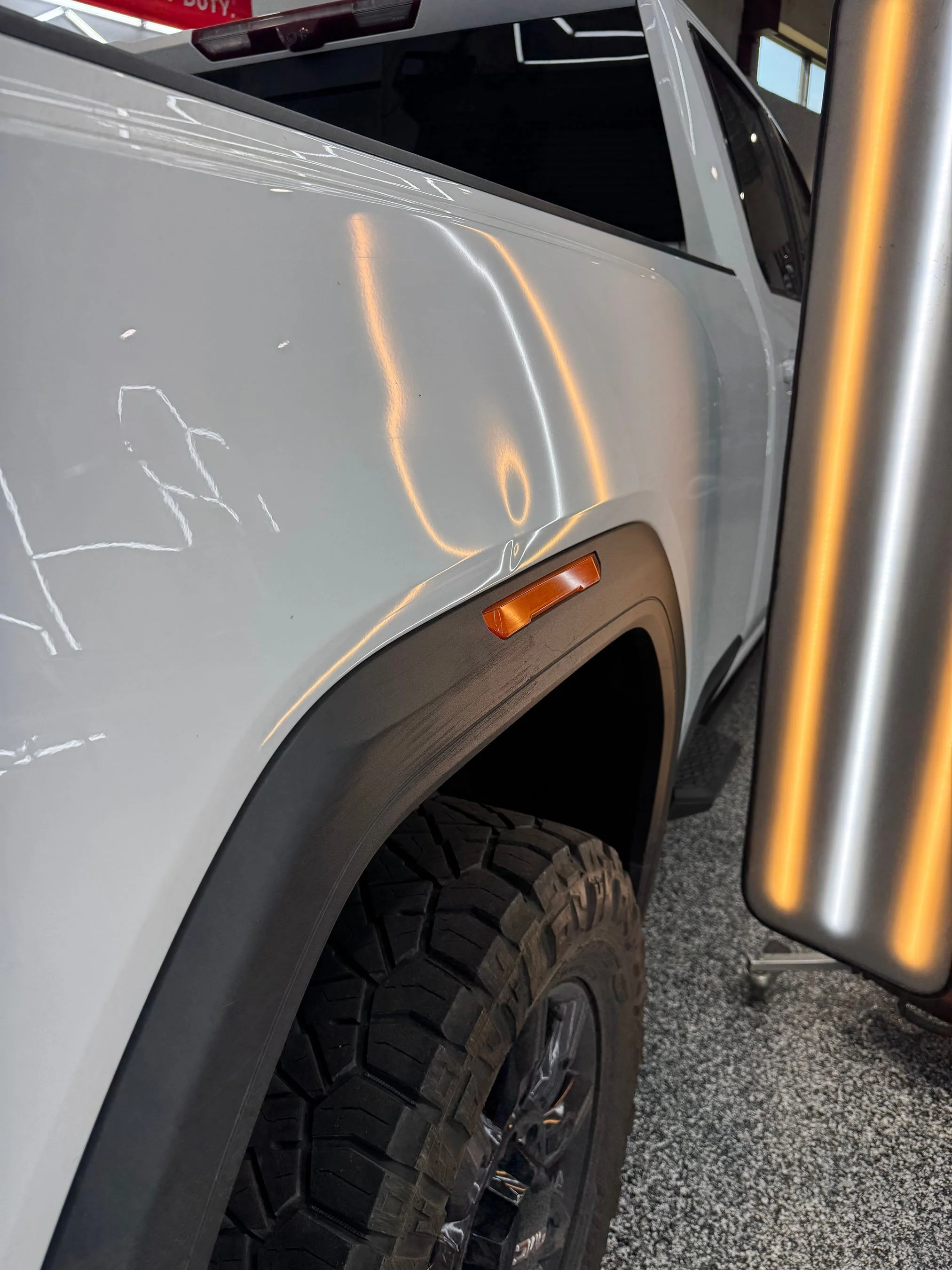 Close-up of a white pickup truck's front side showing a dent.