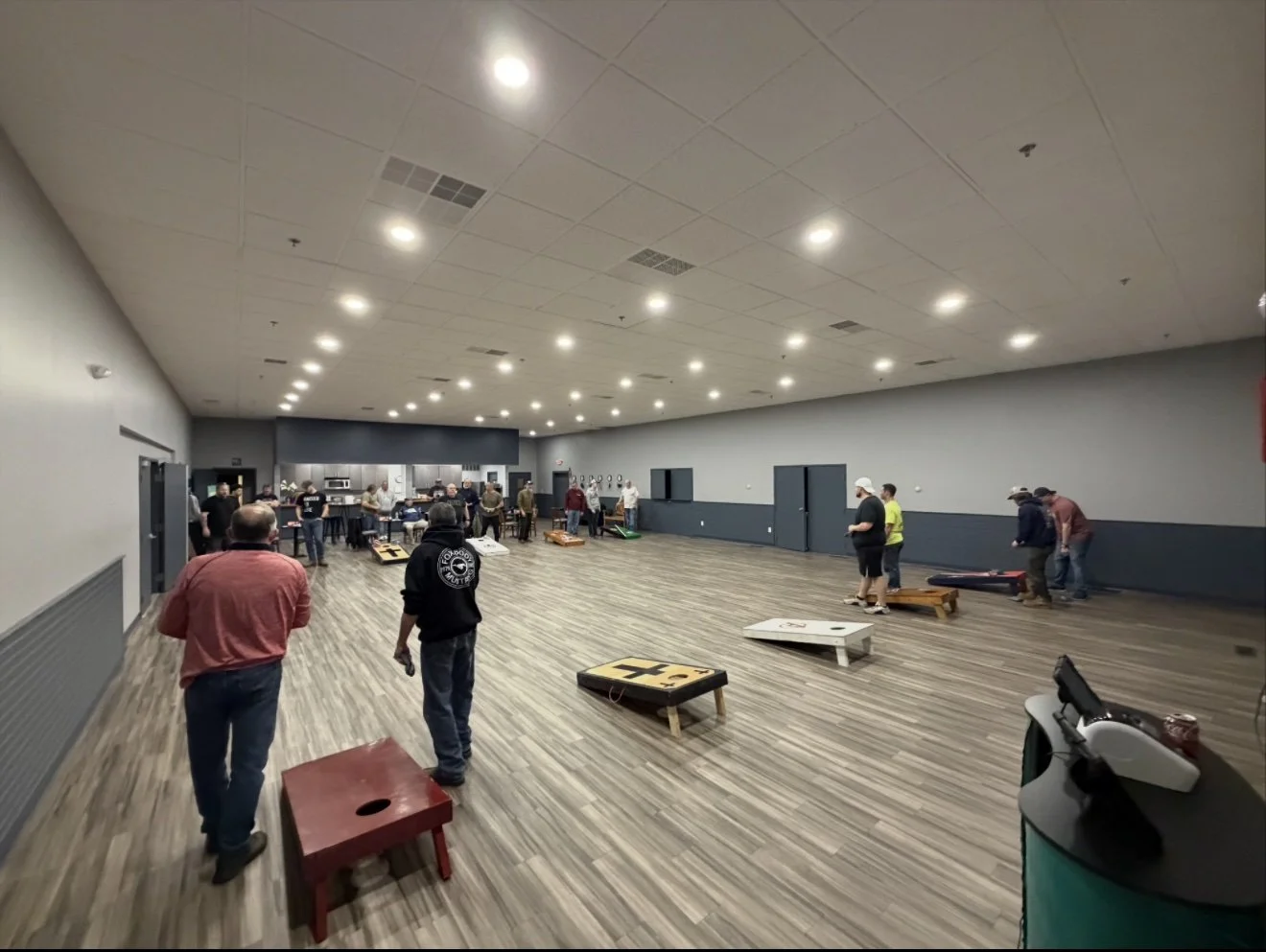 People playing cornhole in a large indoor event hall.