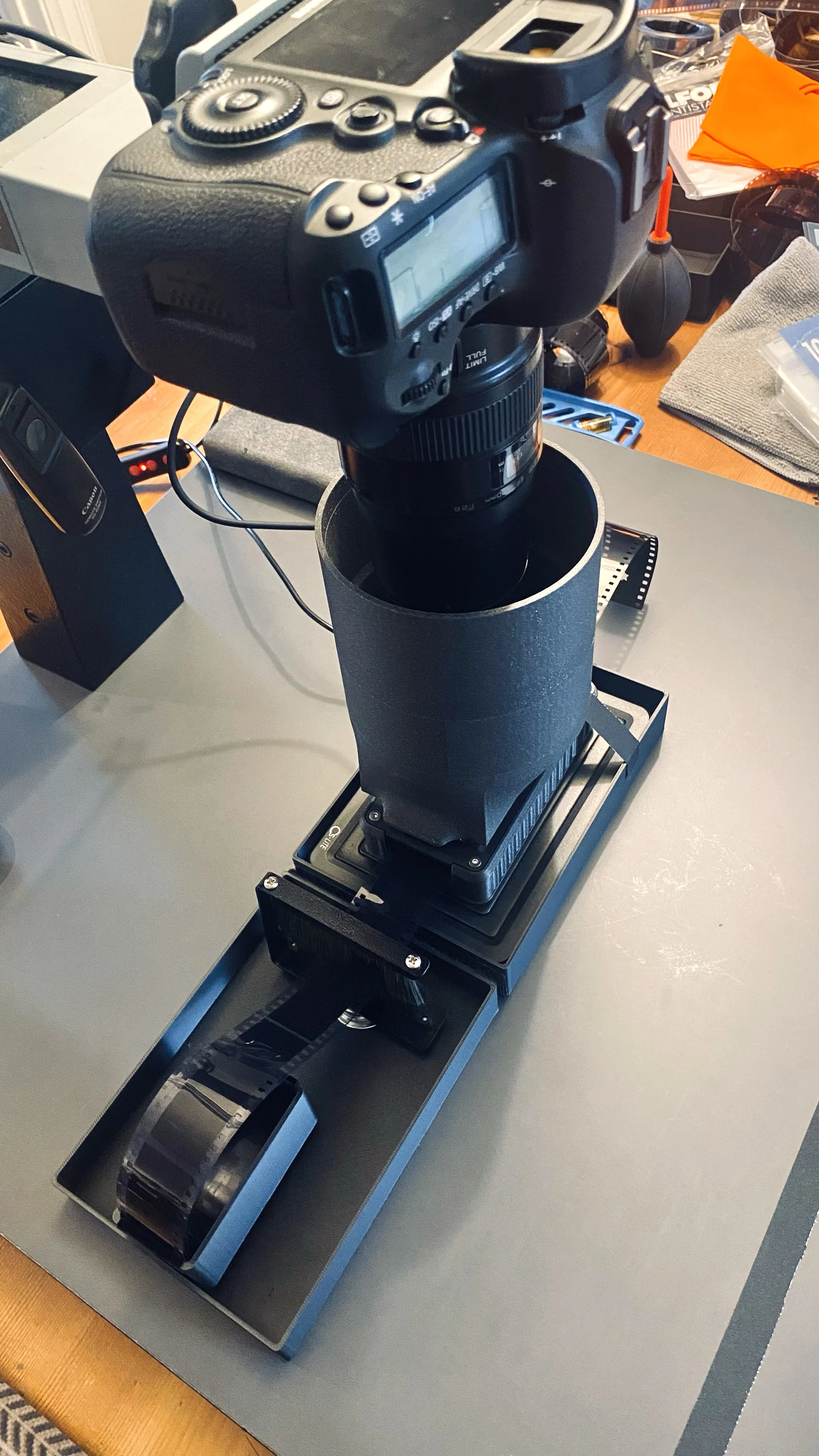 Camera mounted on a device that appears to be a scanner or 3D camera system, positioned on a workspace with various tools and objects around.