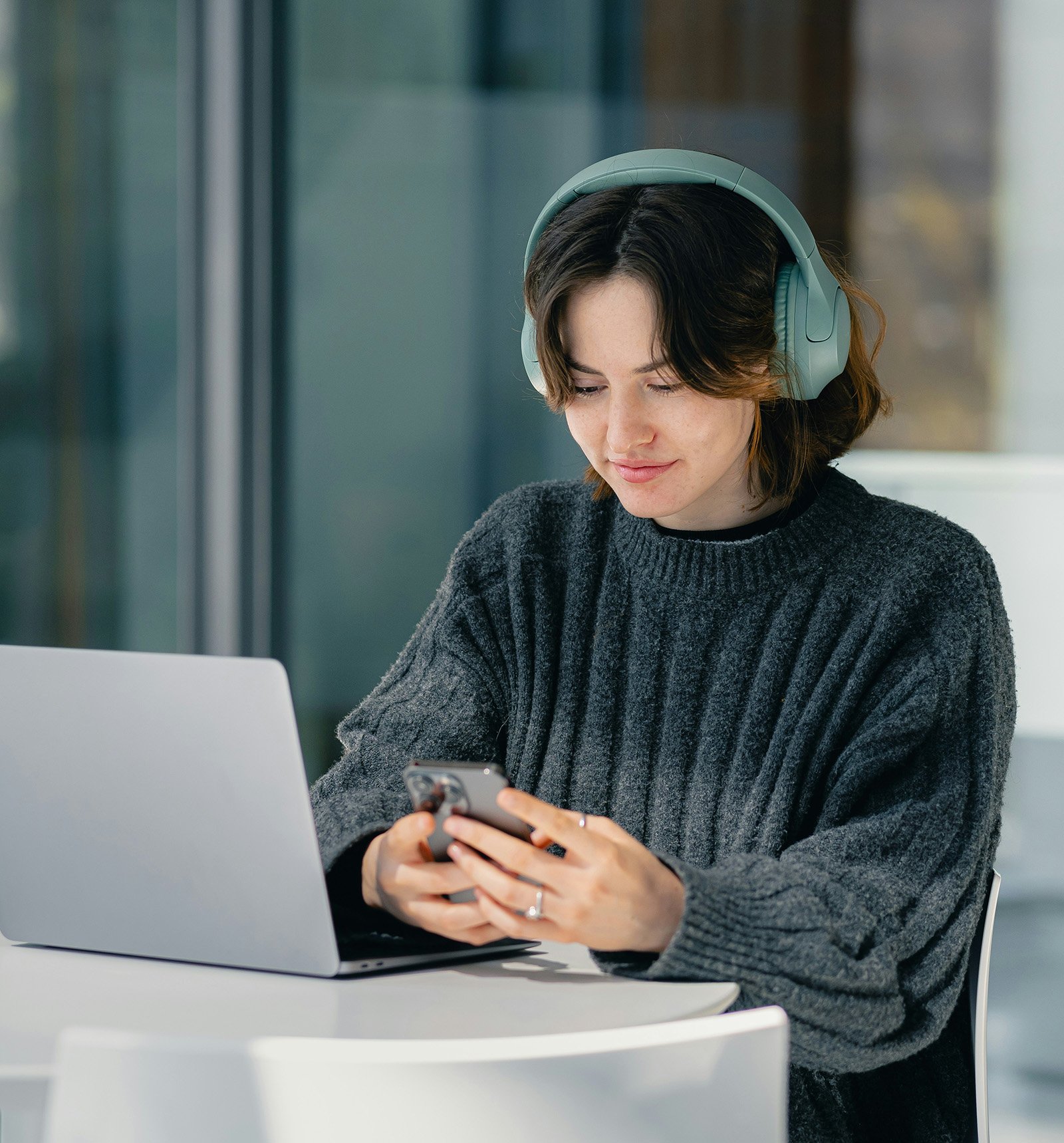 Young adult woman wearing headphones texts on iPhone