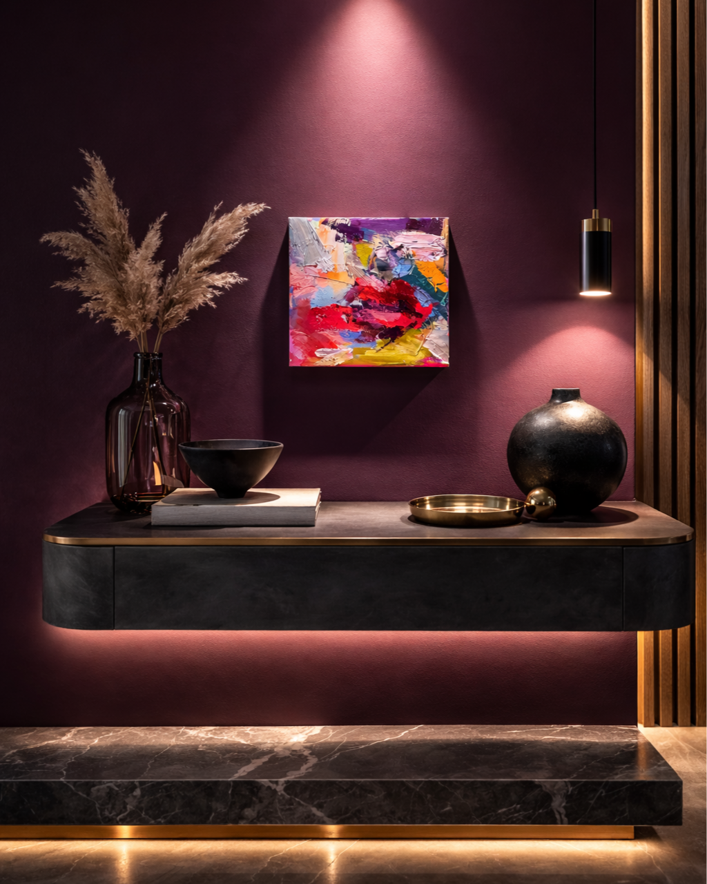Elegant modern entryway with a burgundy wall, abstract artwork, pendant light, pampas grass, decorative vases, and a floating console table.