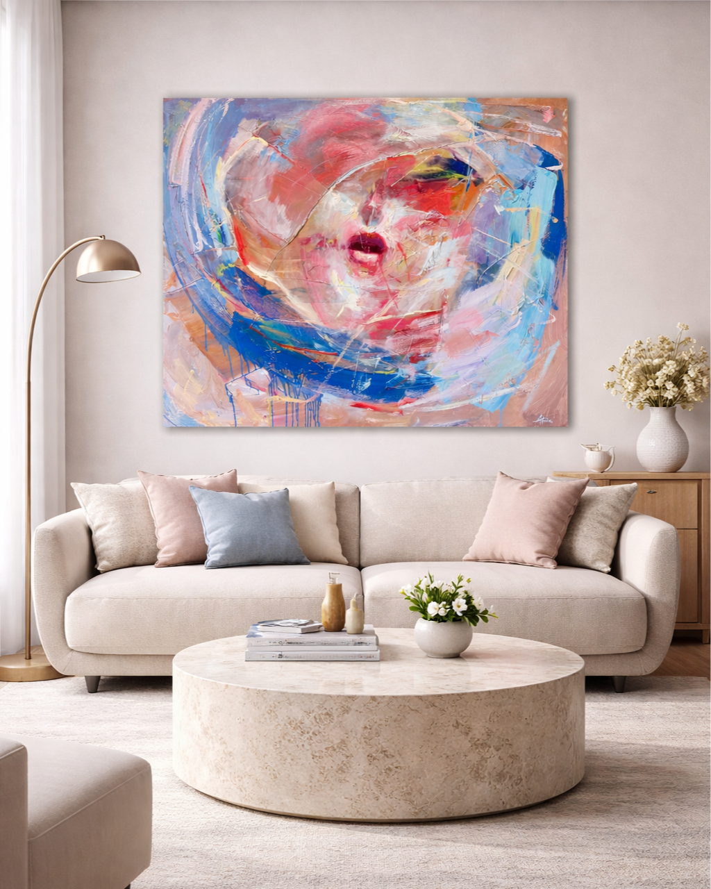 Bright living room with a beige sofa, round marble coffee table, floor lamp, wood cabinet, flowers, and colorful abstract portrait painting