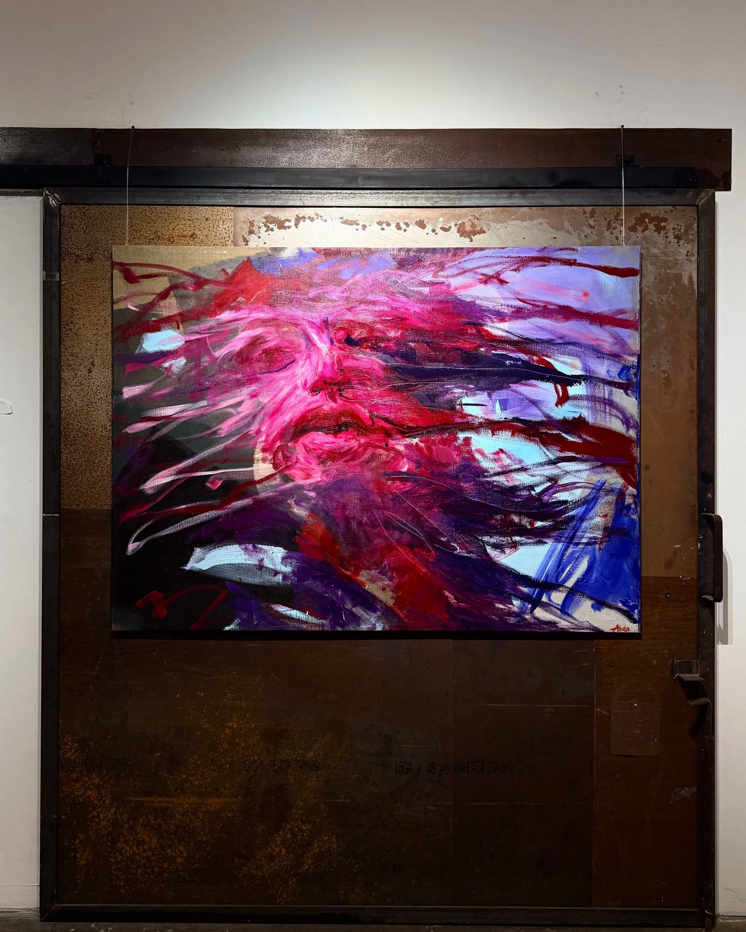 Large abstract painting in vivid pink, red, purple, blue, and black displayed on a dark wooden door.