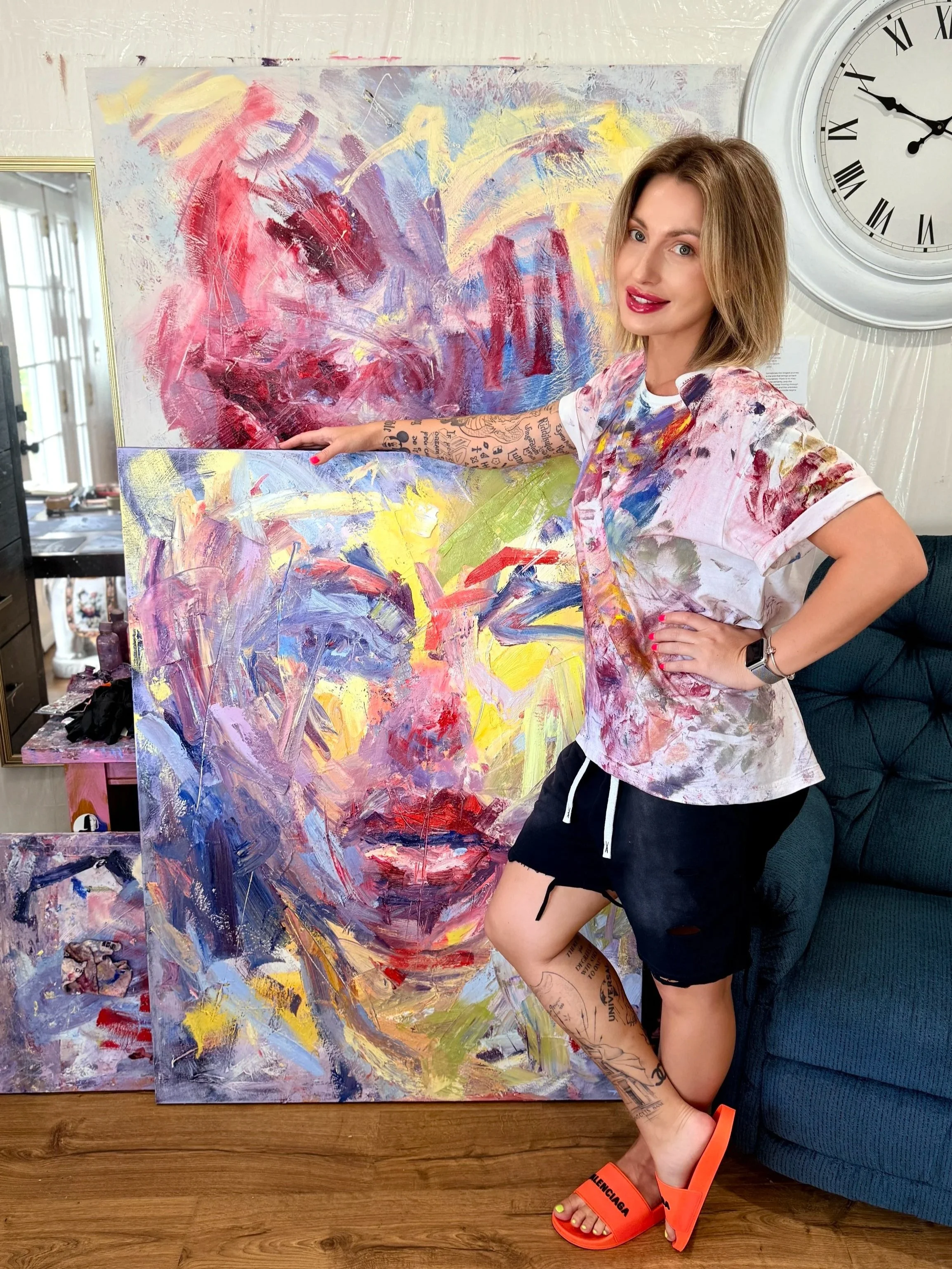 Los Angeles artist Taia Akulova in her studio, standing beside one of her original expressive oil paintings.