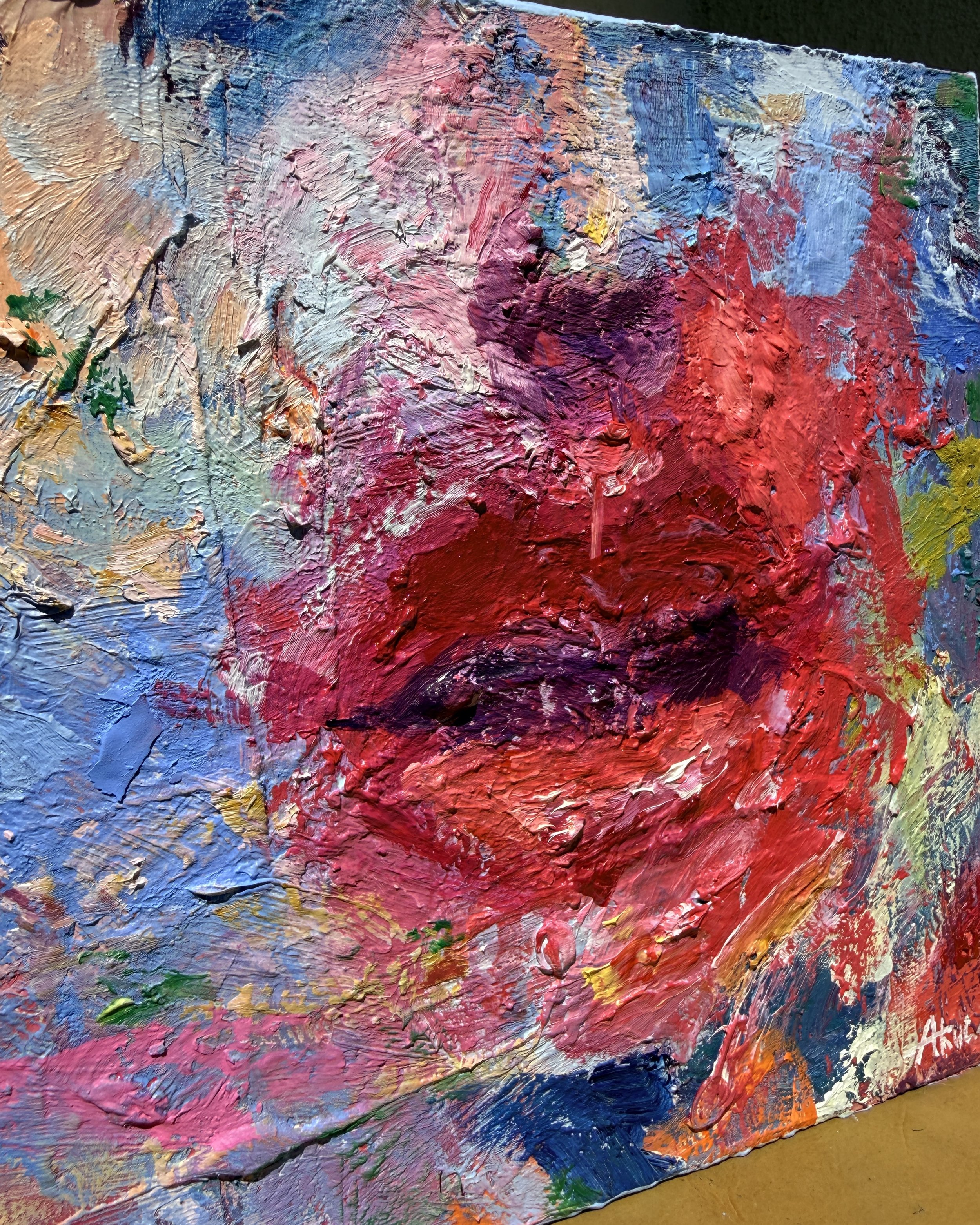 Close-up of heavily textured abstract oil painting in vibrant red, pink, blue, purple, orange, and green hues