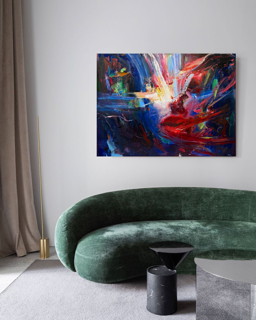 Modern living room with a curved green velvet sofa, abstract colorful painting, black side table, and gray coffee table.