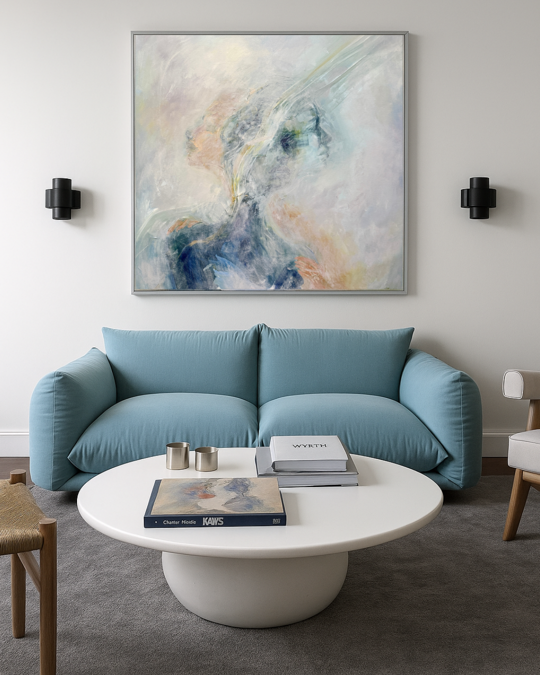 Modern living room with a blue sofa, abstract framed artwork, round white coffee table, art books, and black wall sconces