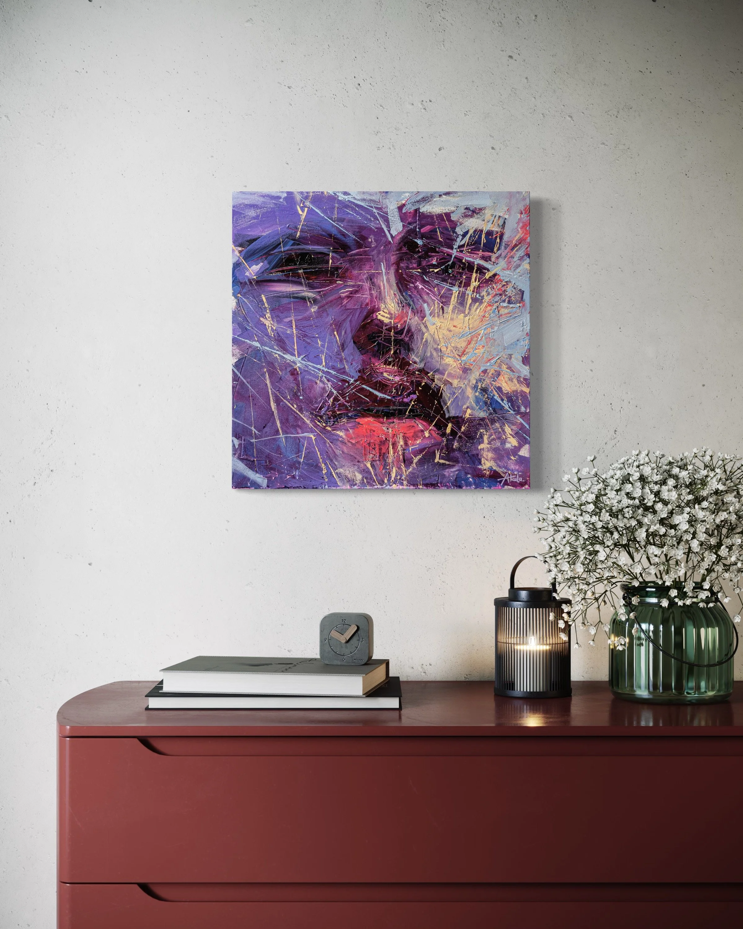 Abstract purple, blue, and red painting above a midcentury cabinet with stacked books, clock, lantern, and white flowers