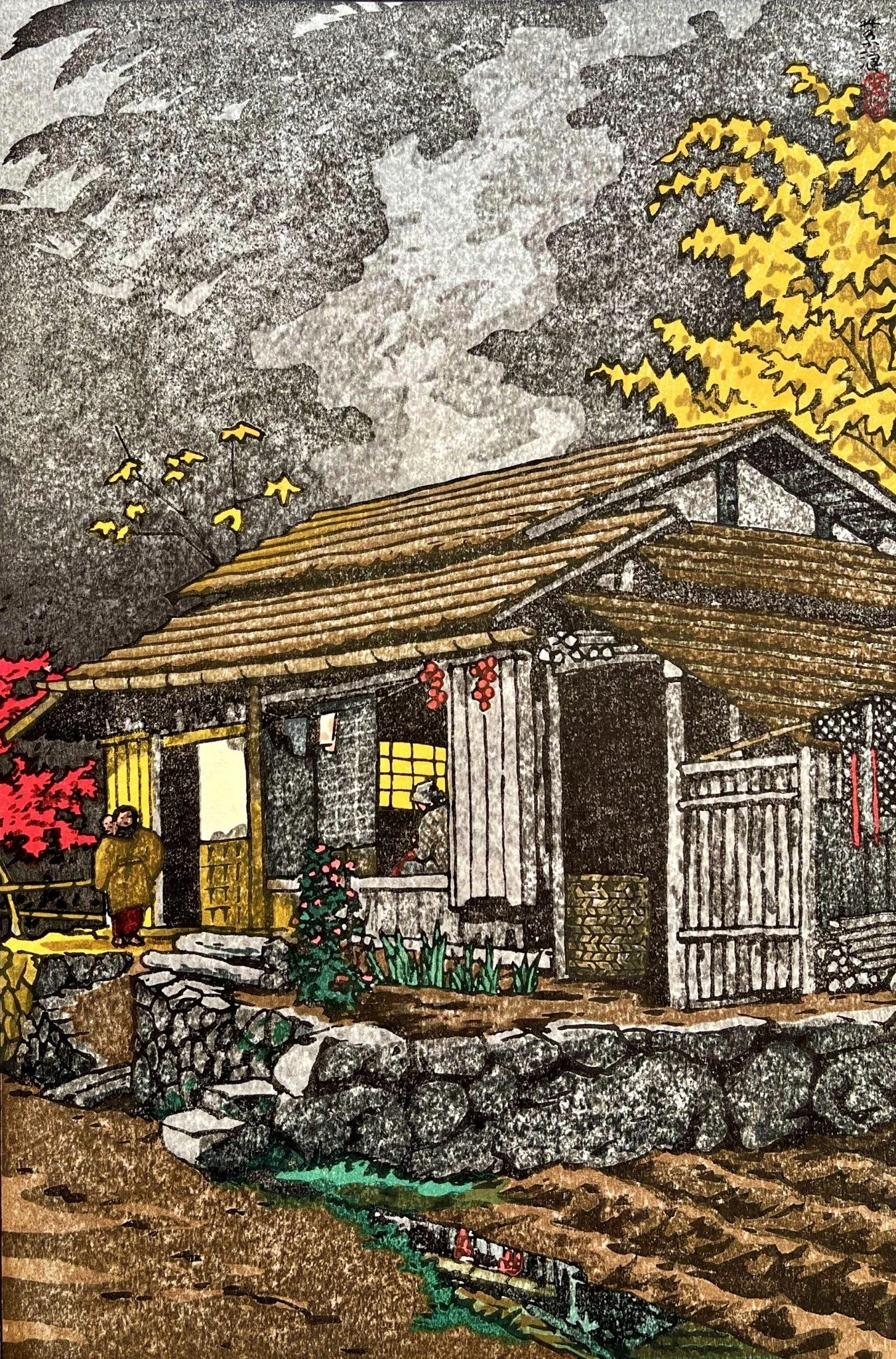 House at Okutama by Shirō Kasamatsu: A wooden house with glowing yellow windows, figures and autumn trees stands above a narrow stream in Kasamatsu’s Okutama scene.