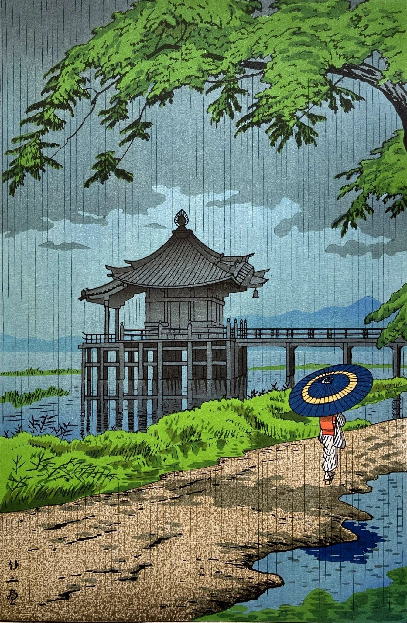 Drizzling Rain at Ukimido by Takeji Asano: A woman with a blue umbrella walks beside Ukimido’s floating hall in fine rain, beneath green branches, by Takeji Asano.