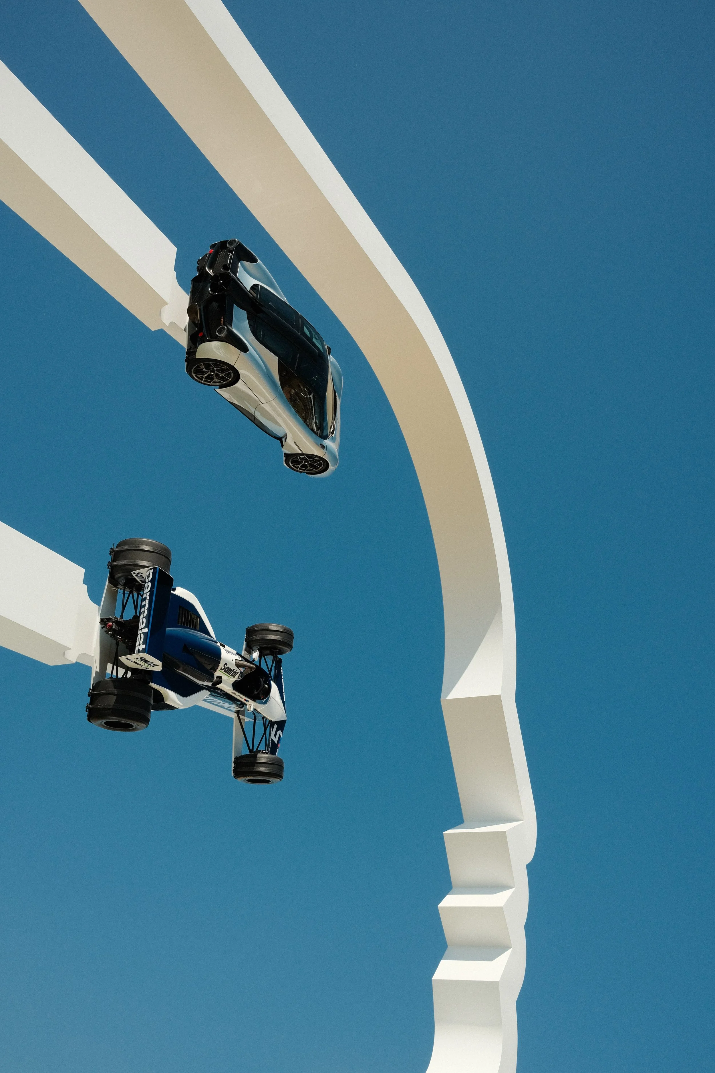 Gordon Murray Automotive T.50 and Brabham BT52 suspended above the Goodwood Festival of Speed central feature against a blue sky.