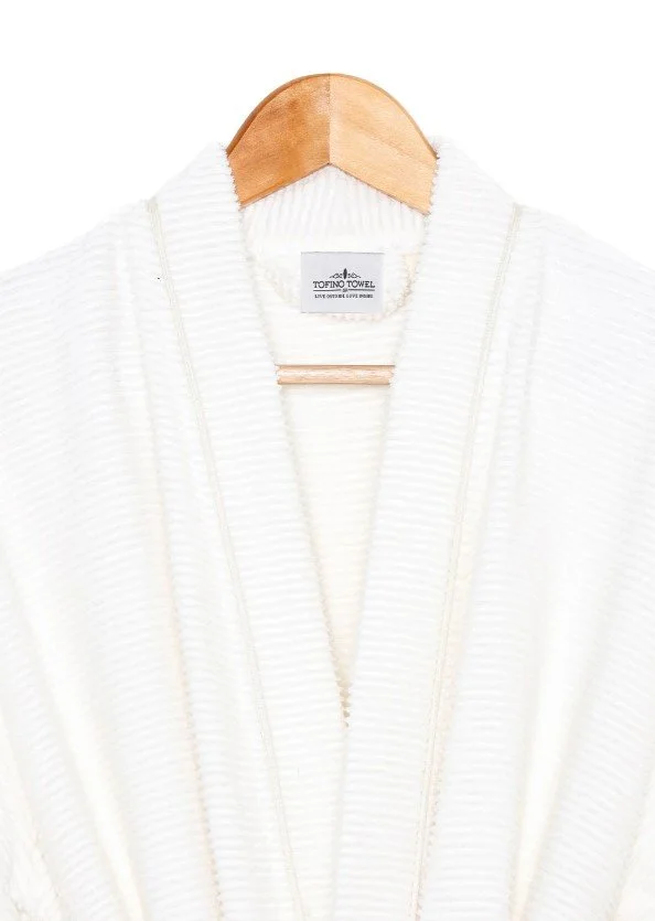 A white textured bathrobe hanging on a wooden hanger against a white background.