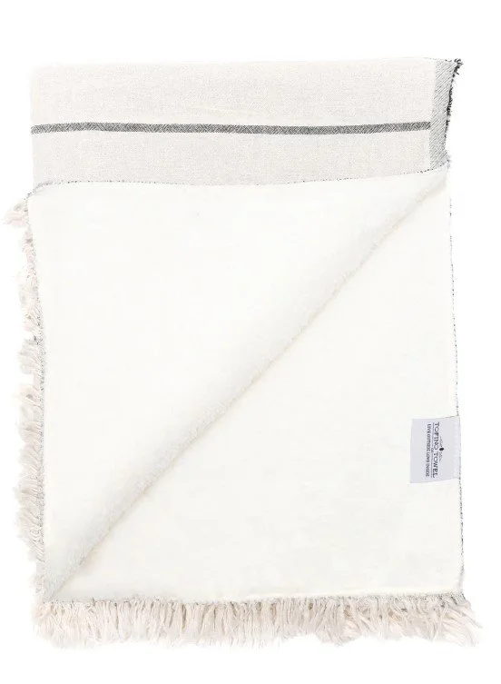 A white towel with fringed edges, one corner folded over, showing a label.