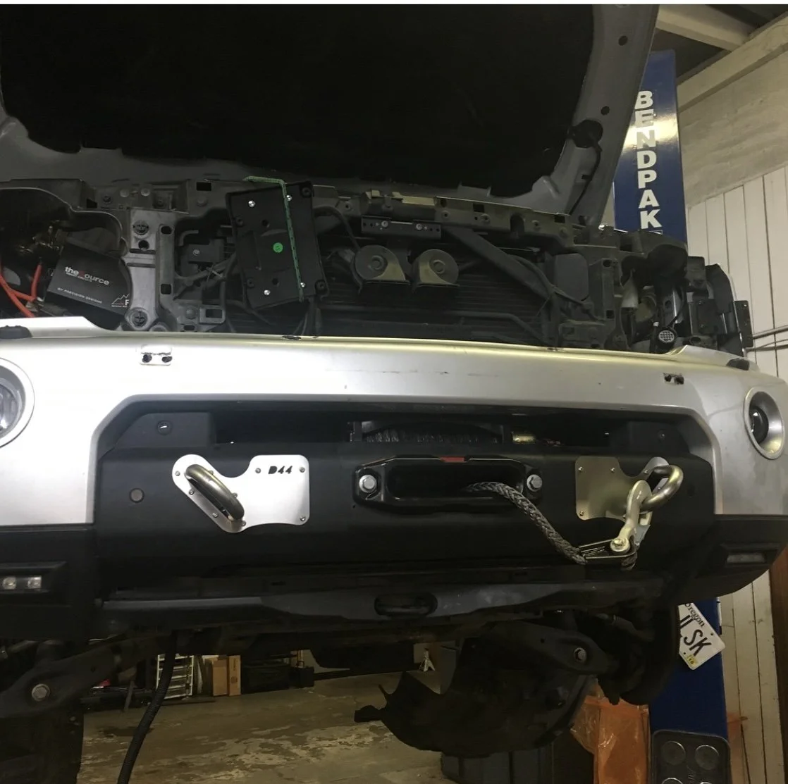 Front of vehicle with hood open, showing internal components and winch attachment on the bumper.