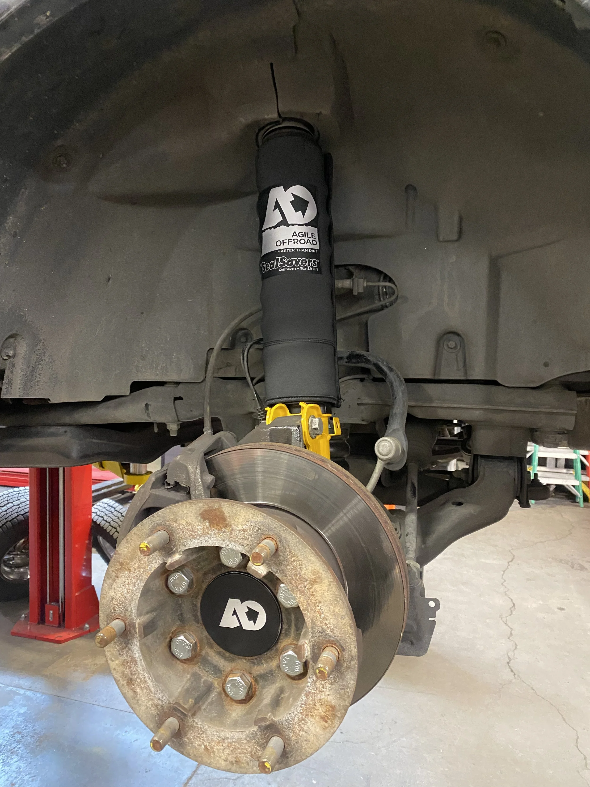 View of a Sprinter vans Agile Offroad front suspension with the wheel removed, showing an aftermarket shock absorber and brake disc.