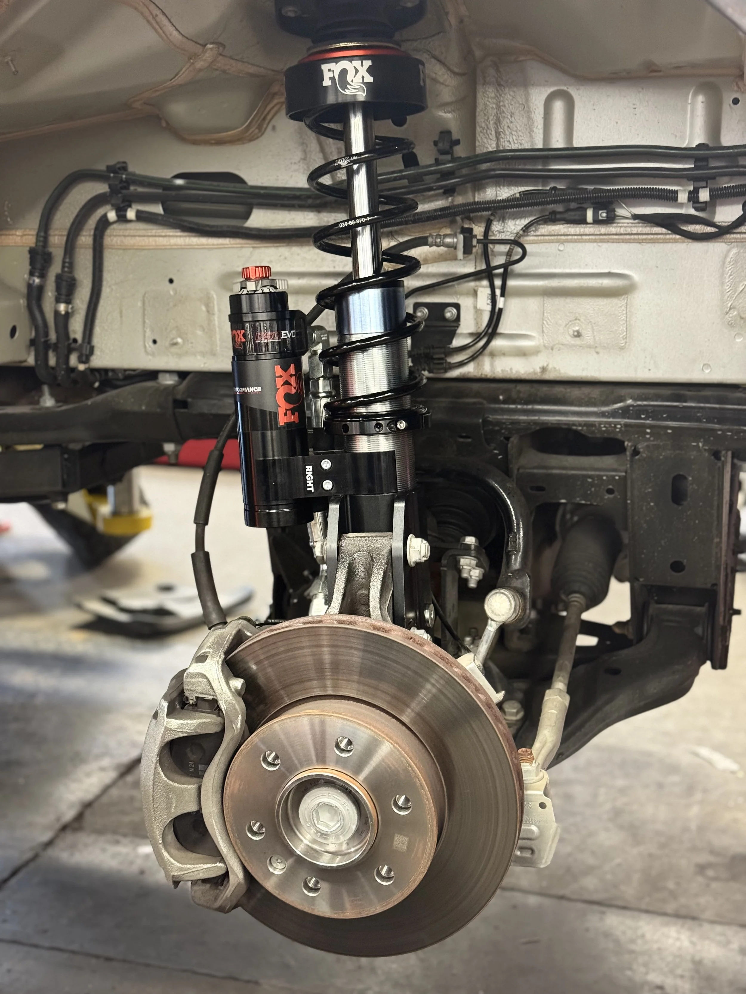 Close-up of a Sprinter Van suspension and brake system, including a Agile Offroad coilover shock absorber, brake caliper, and brake rotor.