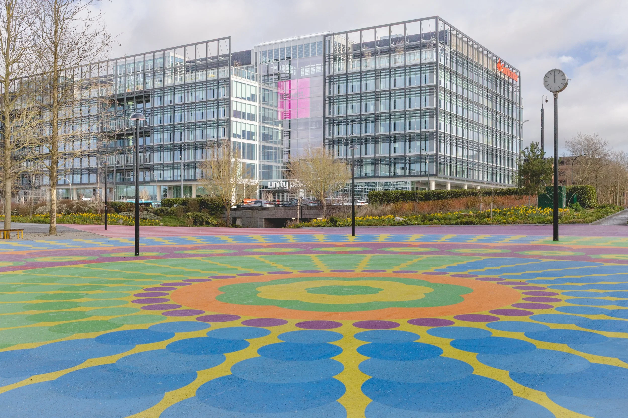 Modern office building with glass windows and a colorful, patterned outdoor area in front