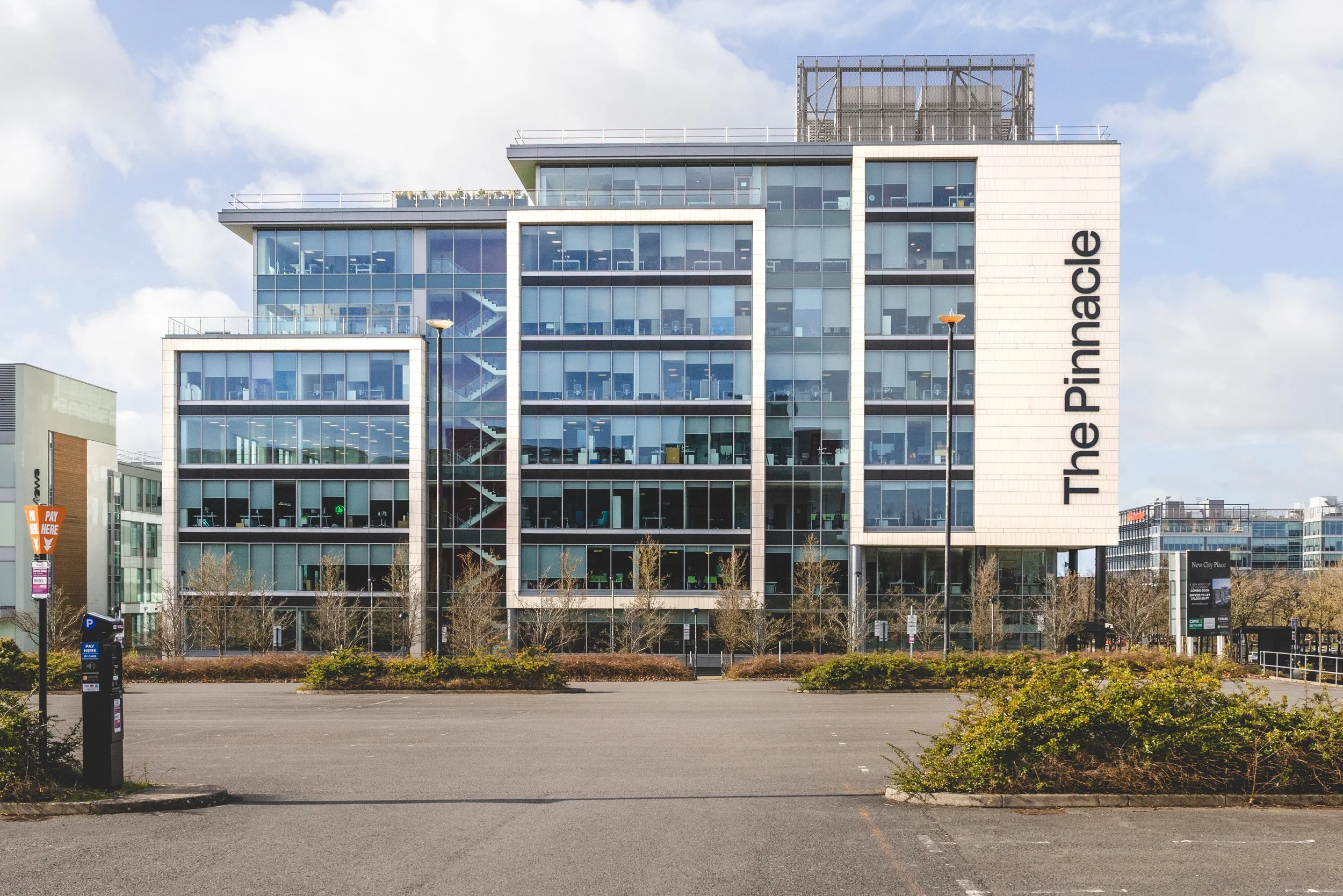 Modern multi-story office building with glass facade and signage that reads 'The Pimmuade'.