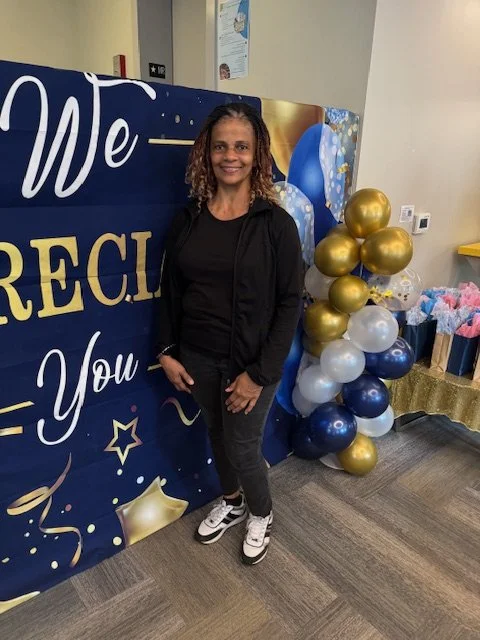 Woman standing in front of a thank you banner with balloon decorations.