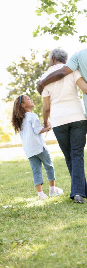 A young girl and an older woman walking with a man in a park, holding hands and sharing a moment of connection.