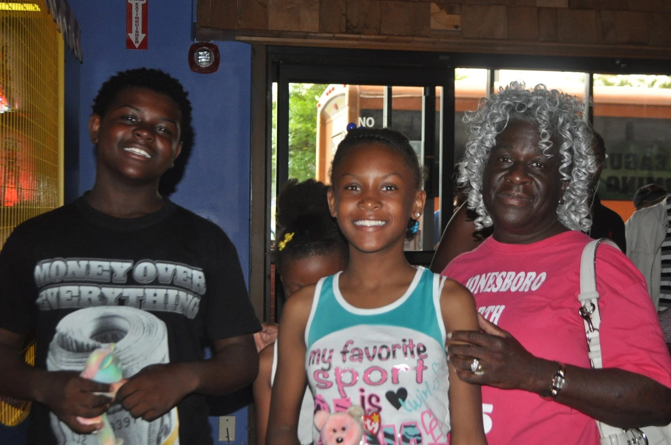Three women and a young girl smiling at a door, standing side by side.