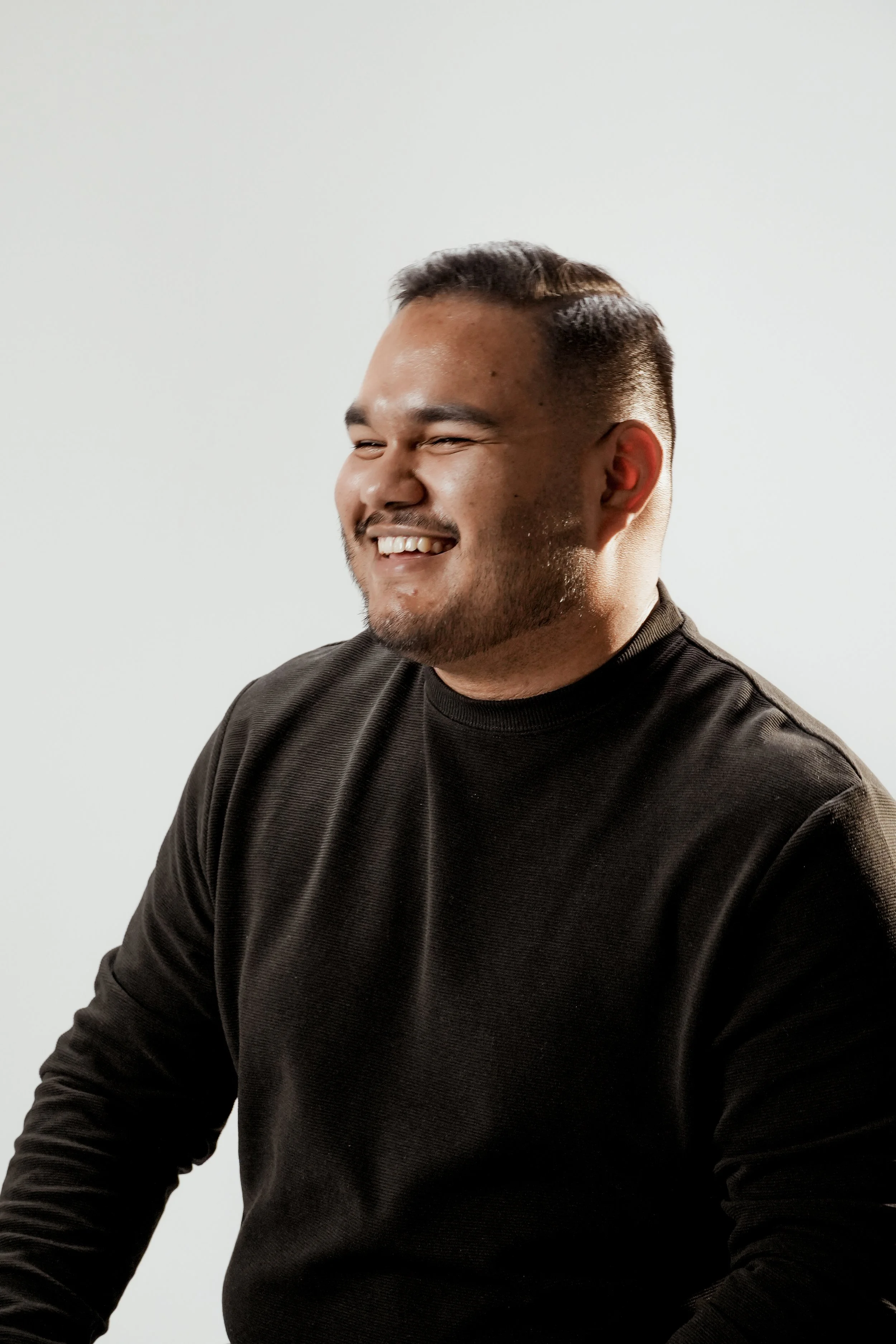 This is Thiago Brasil, the architect. A man with short dark hair, a beard, and a big smile, sitting against a plain white background, wearing a black long-sleeve shirt.