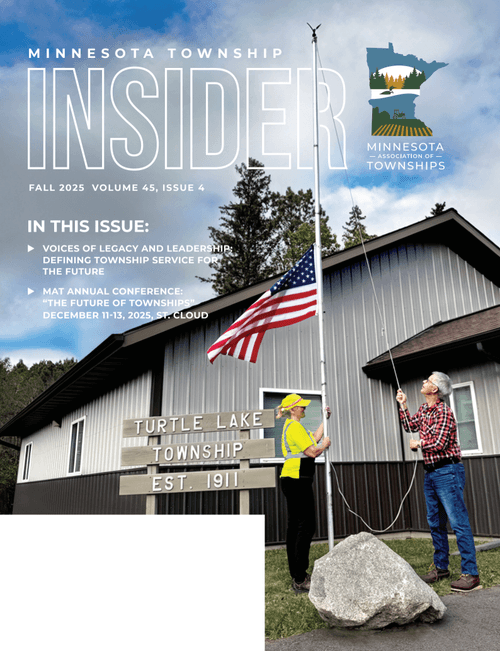 Two women raising an American flag at Turtle Lake Township, established in 1911, with a building and trees in the background and the cover of Minnesota Township Insider magazine.