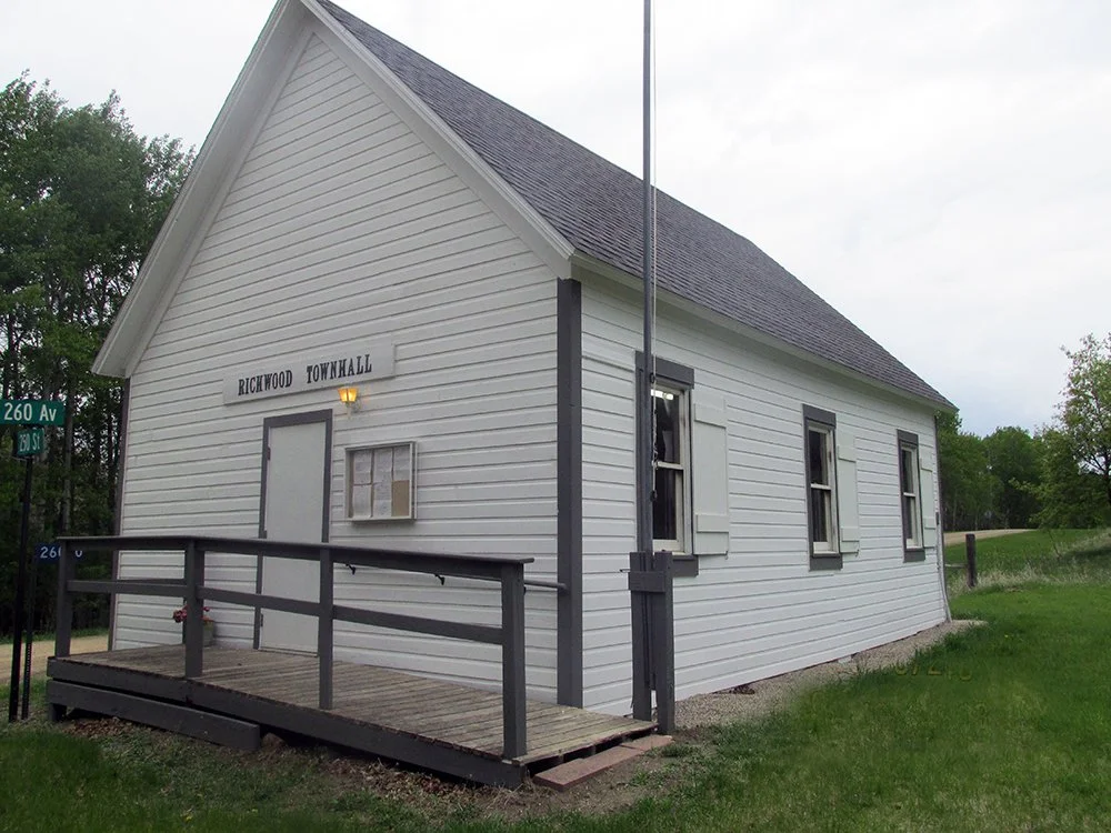 Small white wooden building with a gable roof, labeled "Richwood Townhall," and a small wooden porch with a railing.