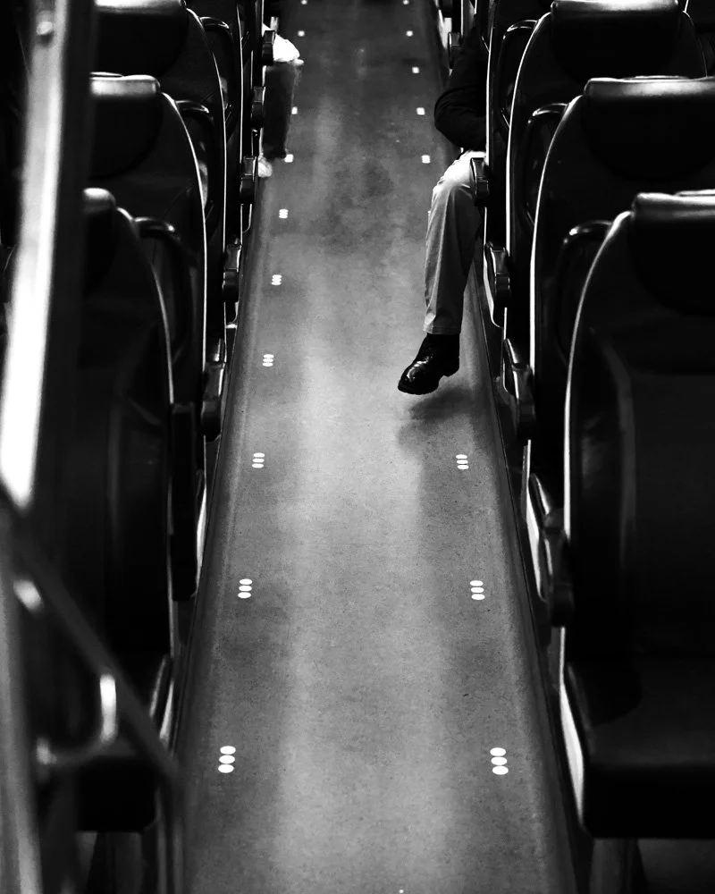 Empty airplane aisle with a person sitting on the right side of the aisle.