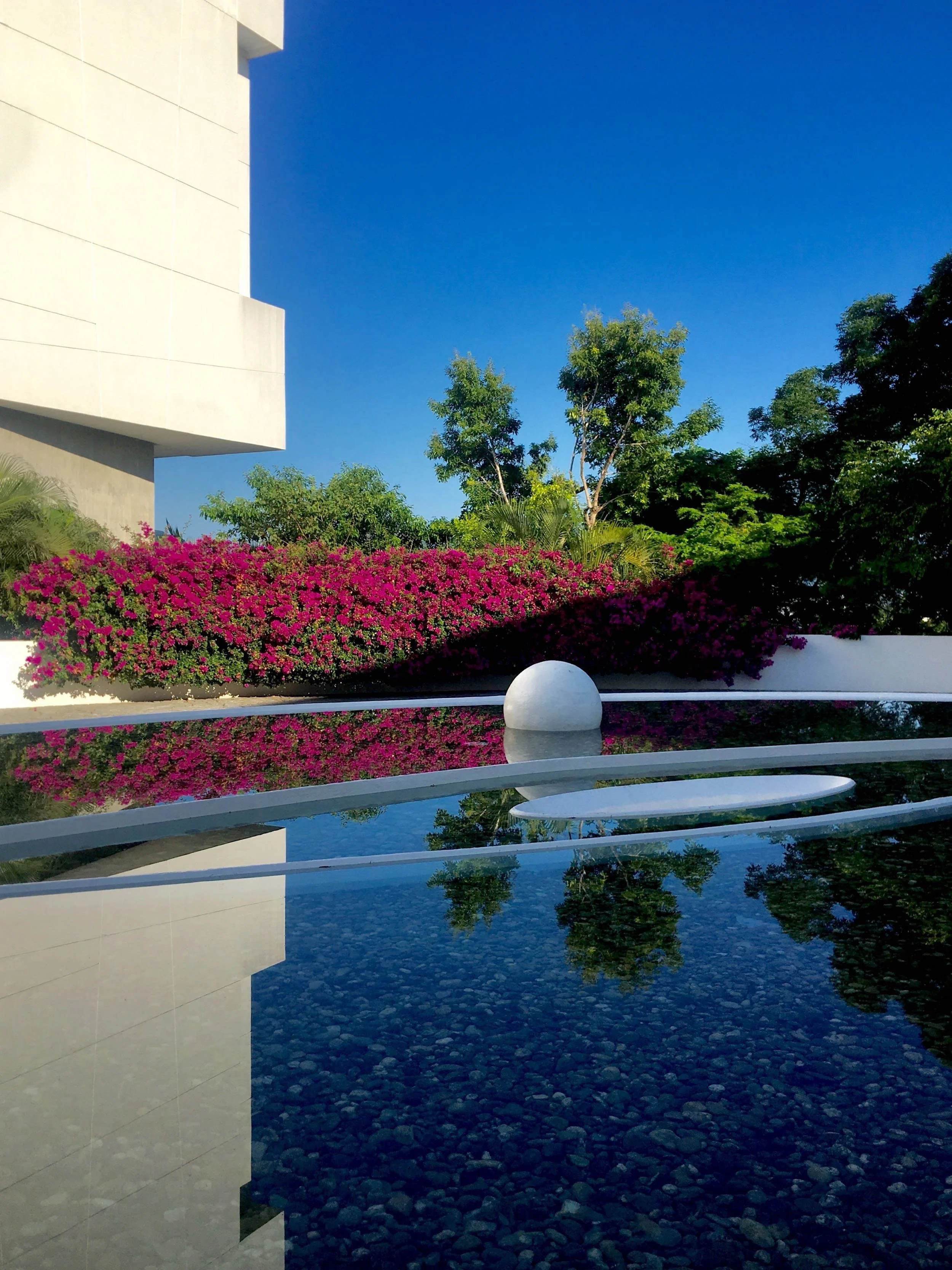 Esfera blanca flotando sobre simetría de agua y concreto. Hotel Encanto Acapulco de Miguel Ángel Aragonés.