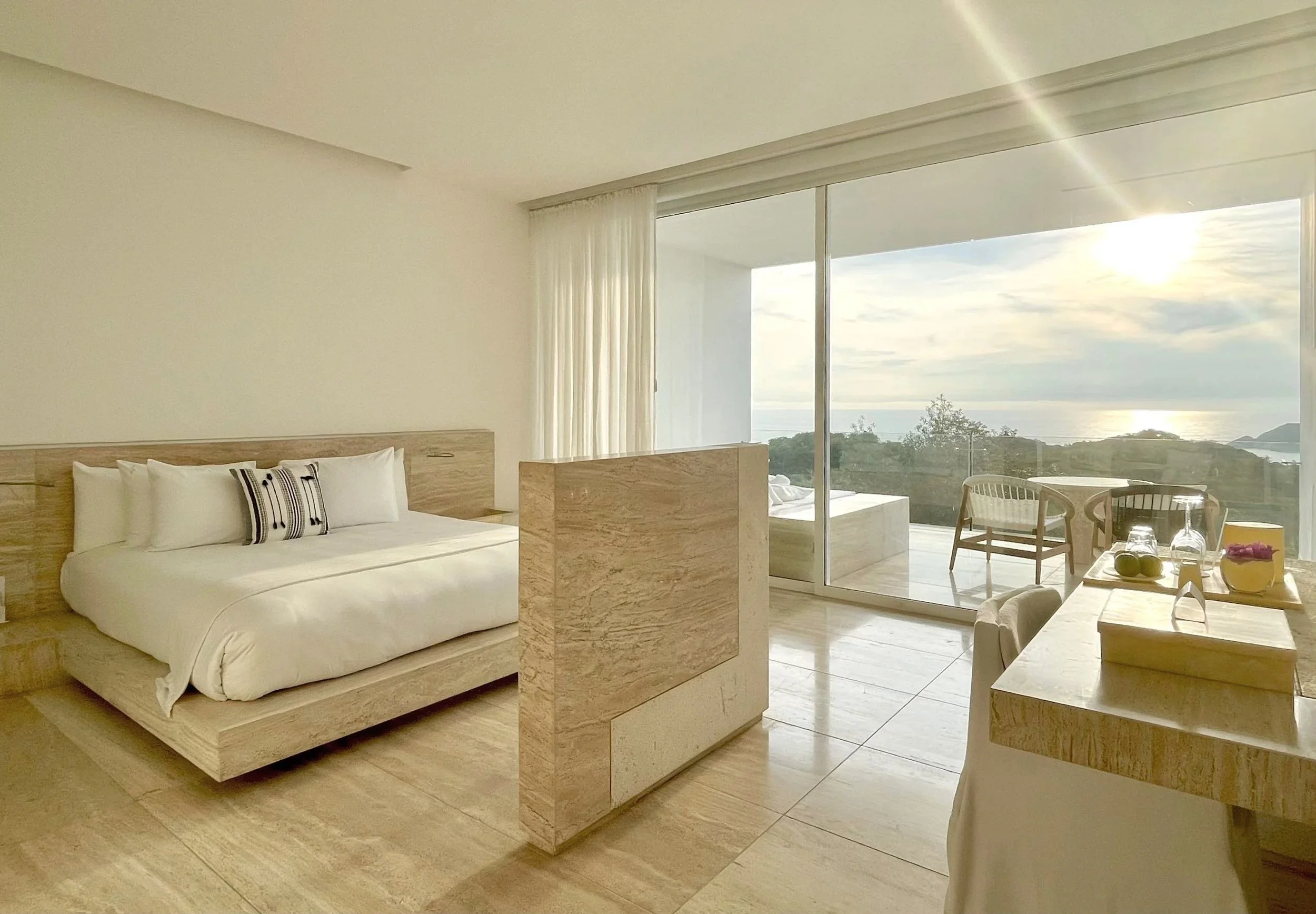 Perspectiva de la cama e interiores en madera de la Ocean Balcony Suite en Hotel Encanto. Espacios a escala humana.