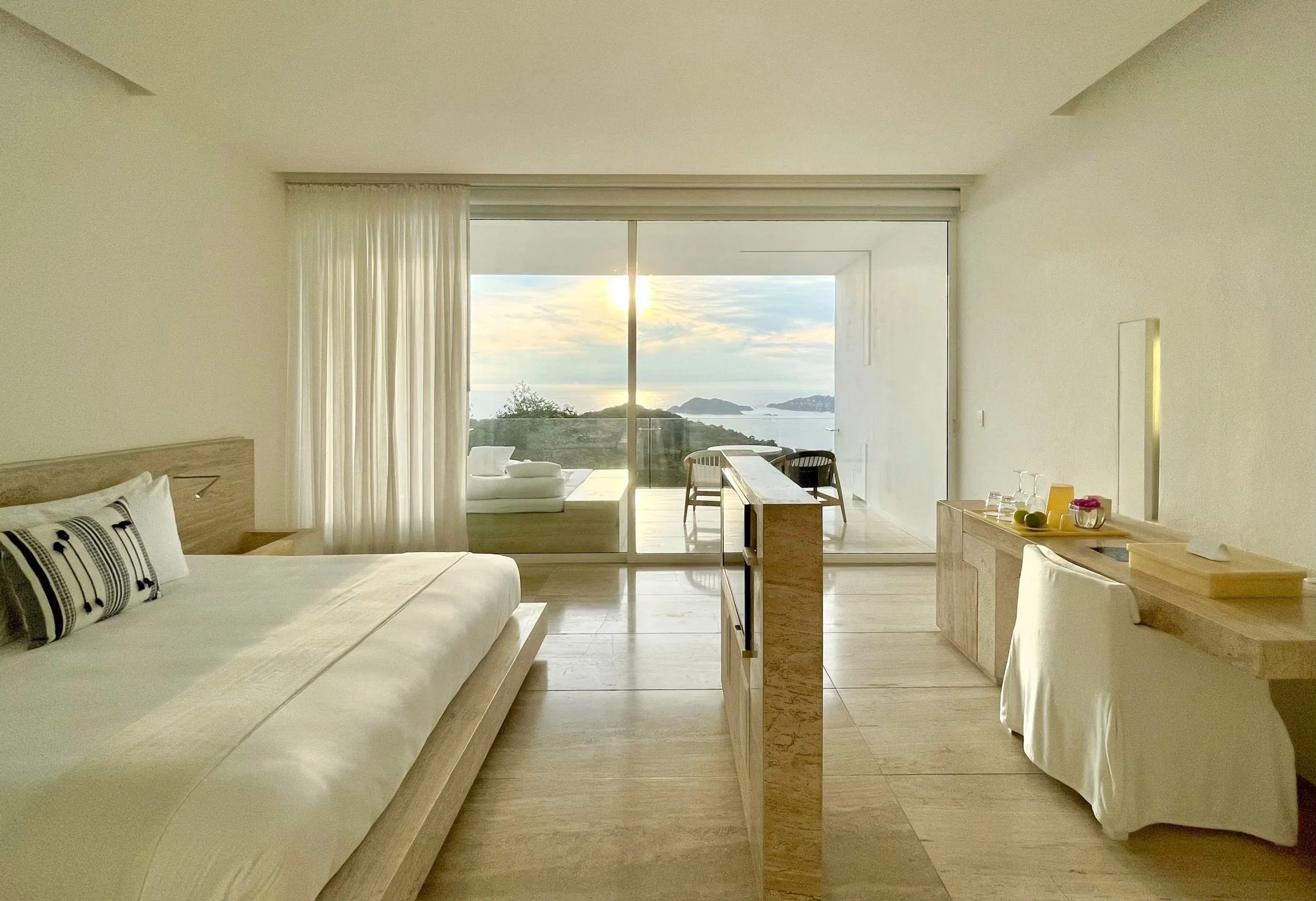 Cama de día exterior enmarcada por muros minimalistas en la Ocean Balcony Suite de Hotel Encanto. Pulsión por el mar.