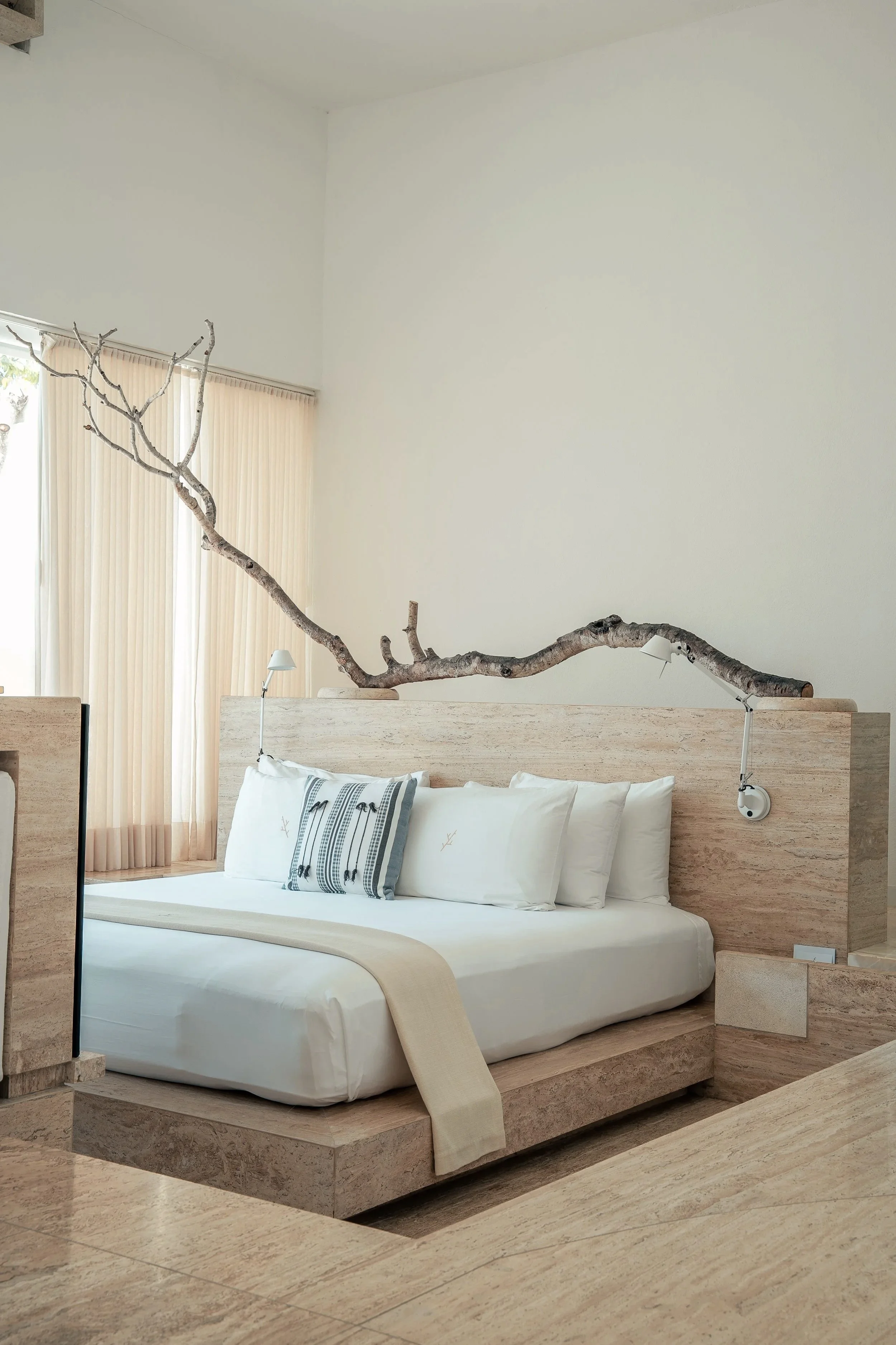 Cama con cabecera de mármol travertino y rama orgánica en Hotel Encanto Acapulco. Diseño minimalista de Taller Aragonés.