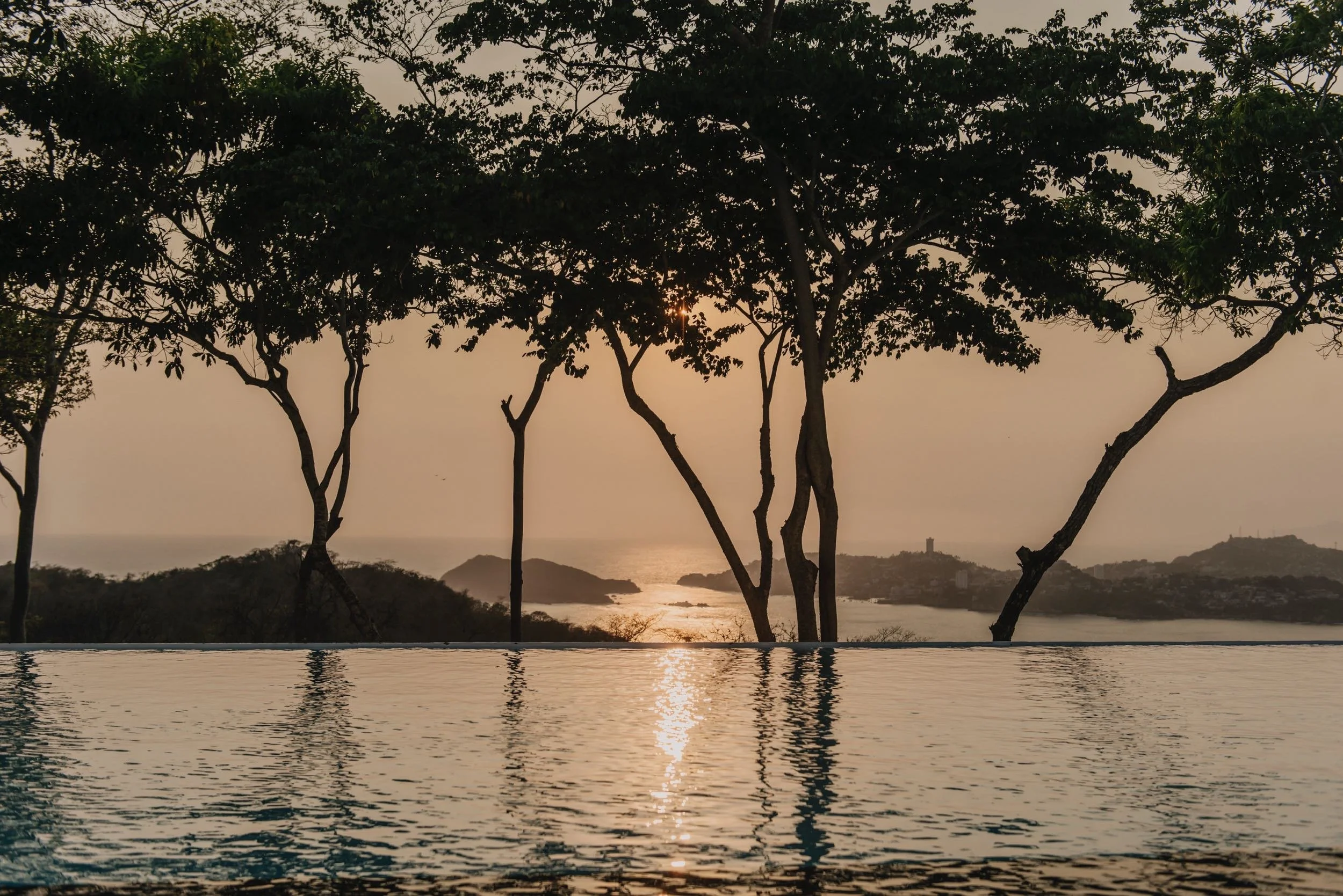 Oceáno Pacífico y árboles desde la piscina infinita de Hotel Encanto Acapulco. Escenario natural y pulsión por el mar.