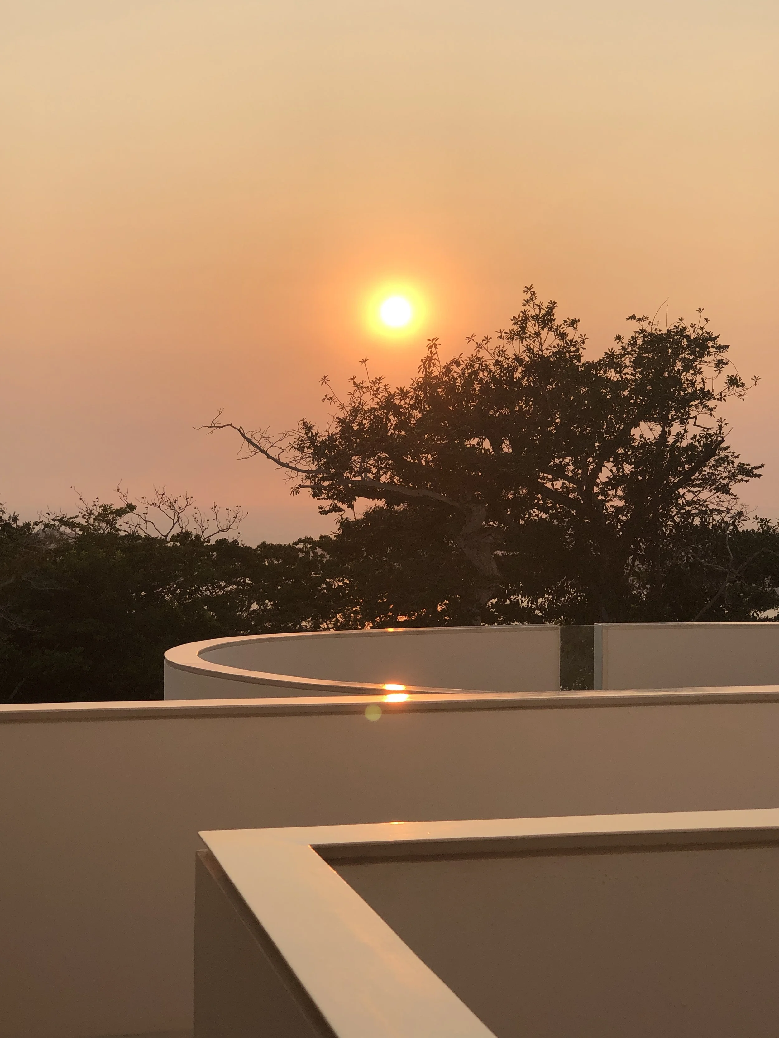 Muros curvos de concreto blanco frente al ocaso en Hotel Encanto Acapulco. Arquitectura y escala humana en Brisas Marqués.